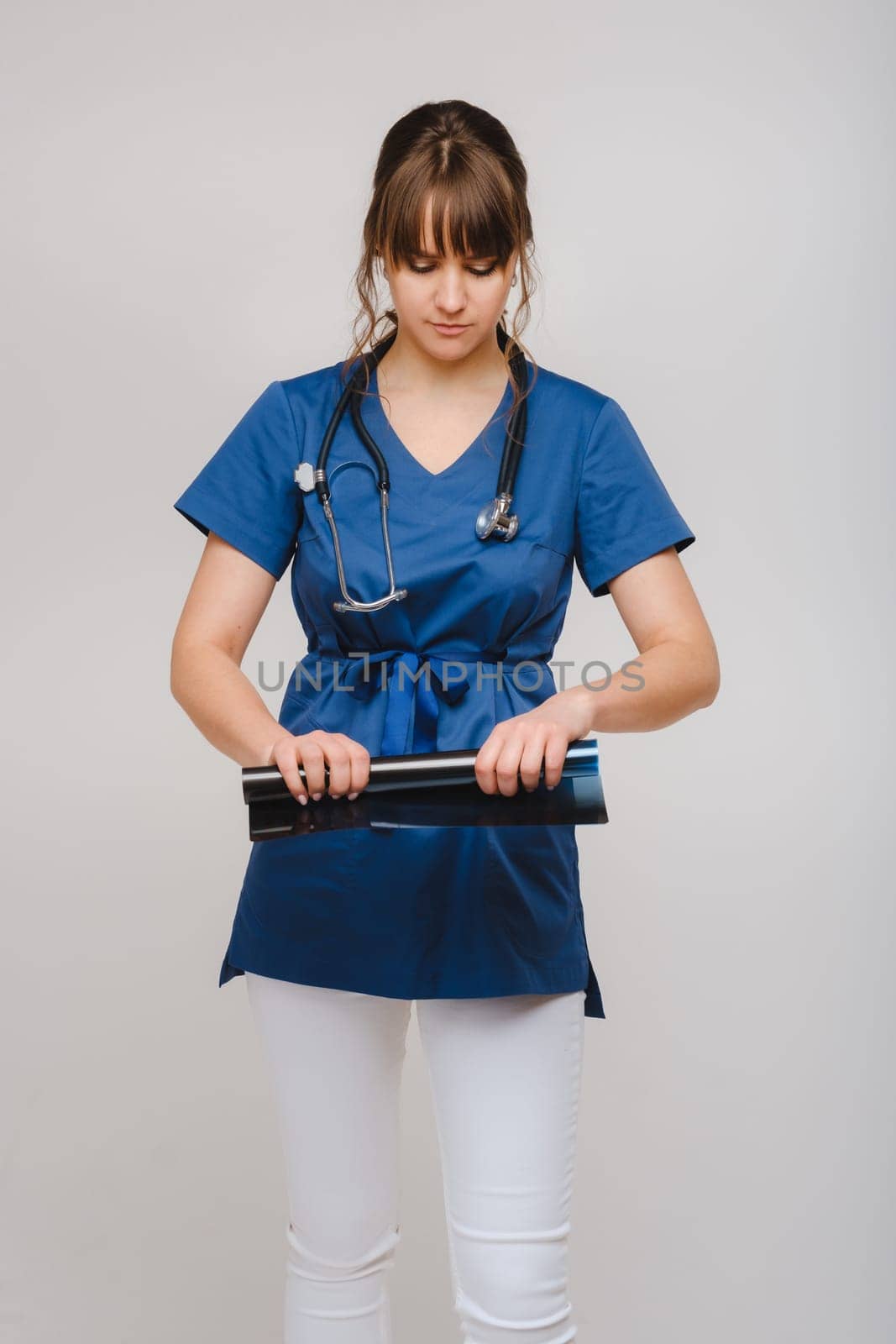 Female Brunette Doctor Looking at Tomography X-ray Film by Lobachad