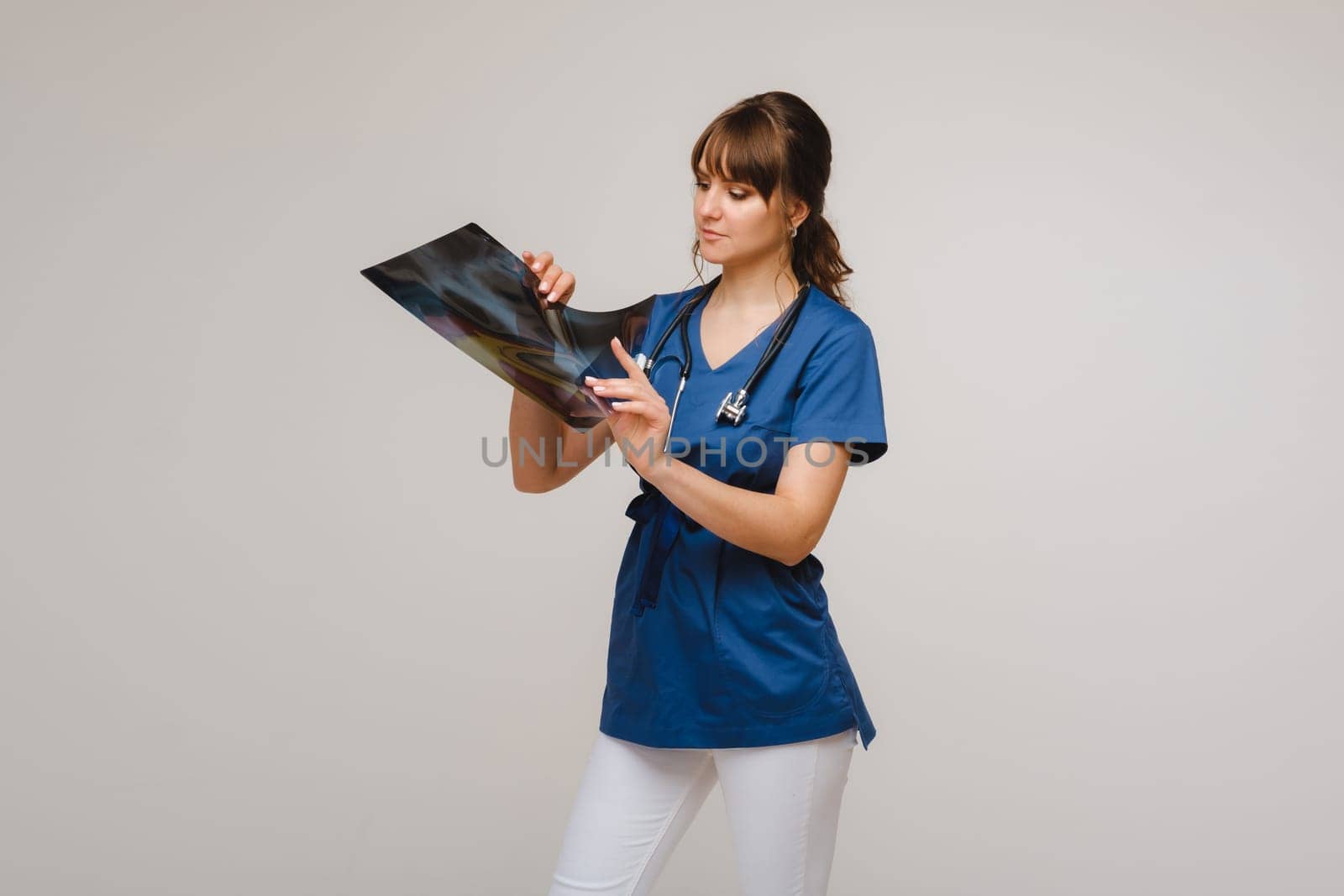 Female Brunette Doctor Looking at Tomography X-ray Film by Lobachad