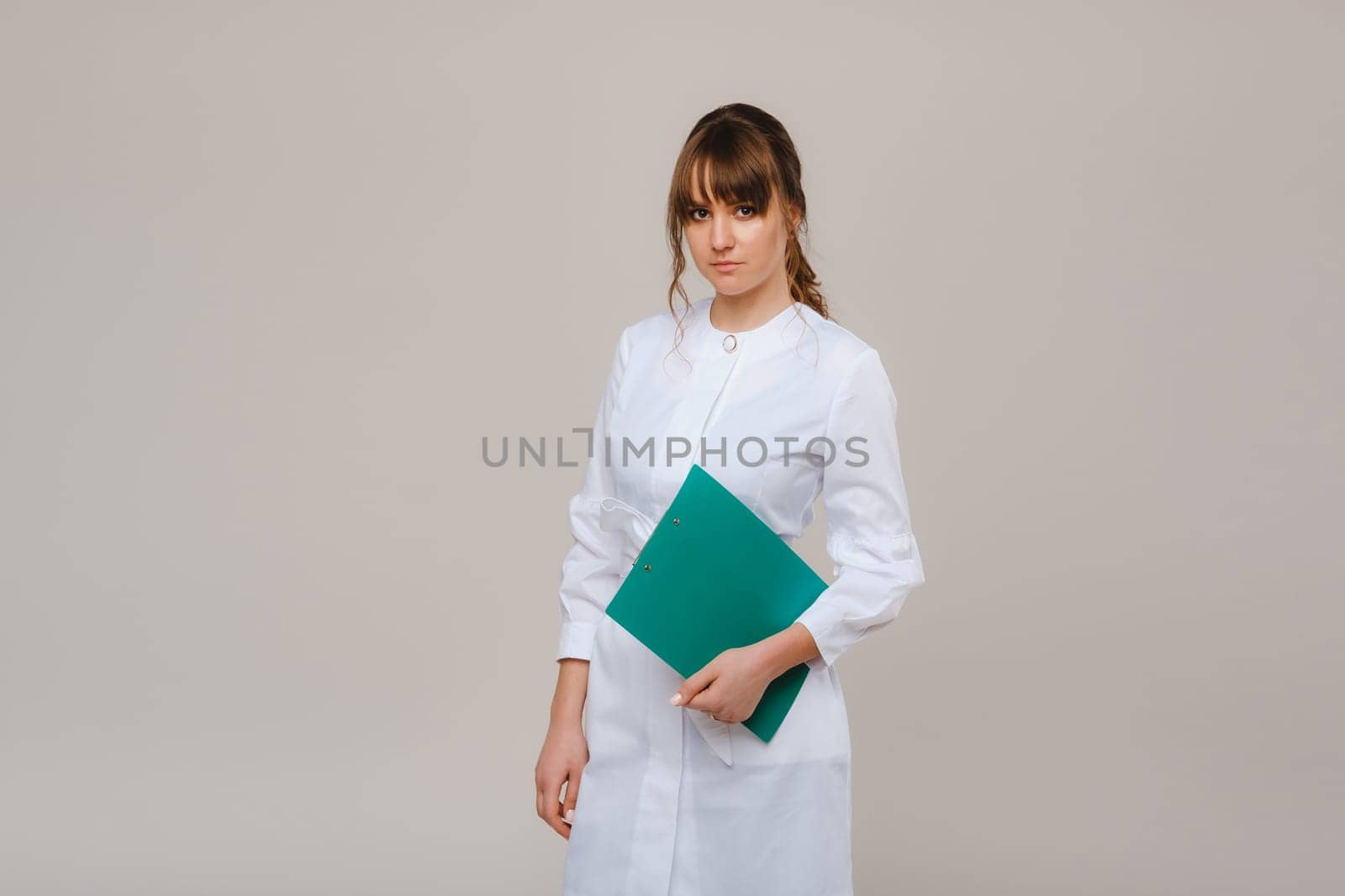 Portrait of a female medical worker in a gray background with a medical report.Girl doctor with a Notepad.