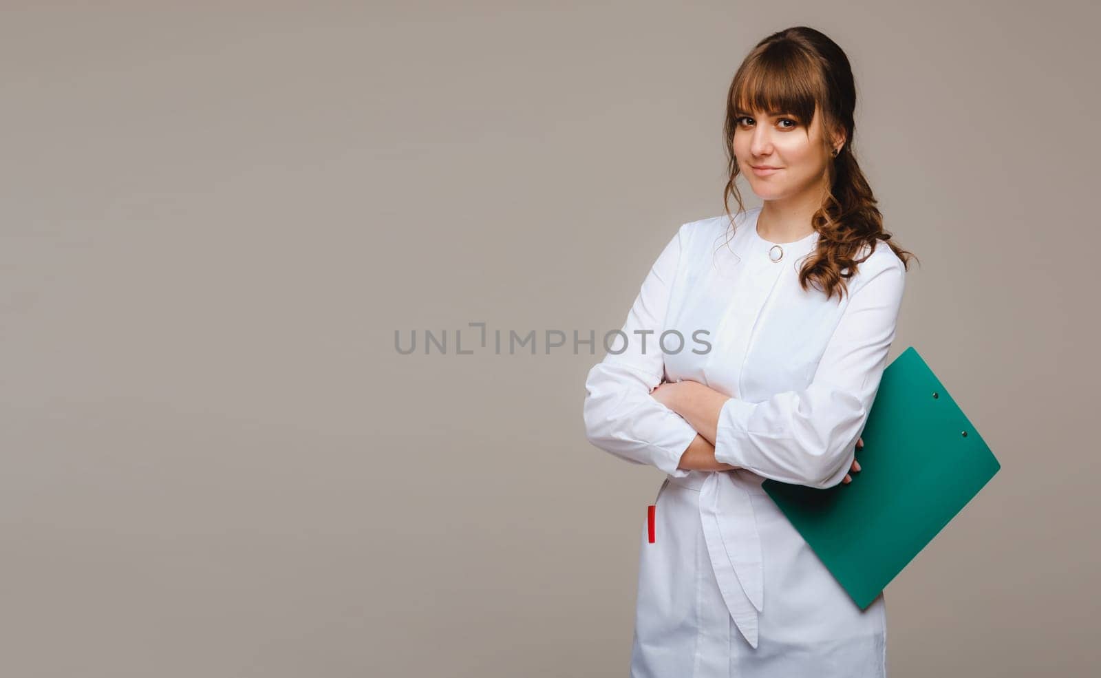 a female doctor with a notebook in her hands on a gray background by Lobachad