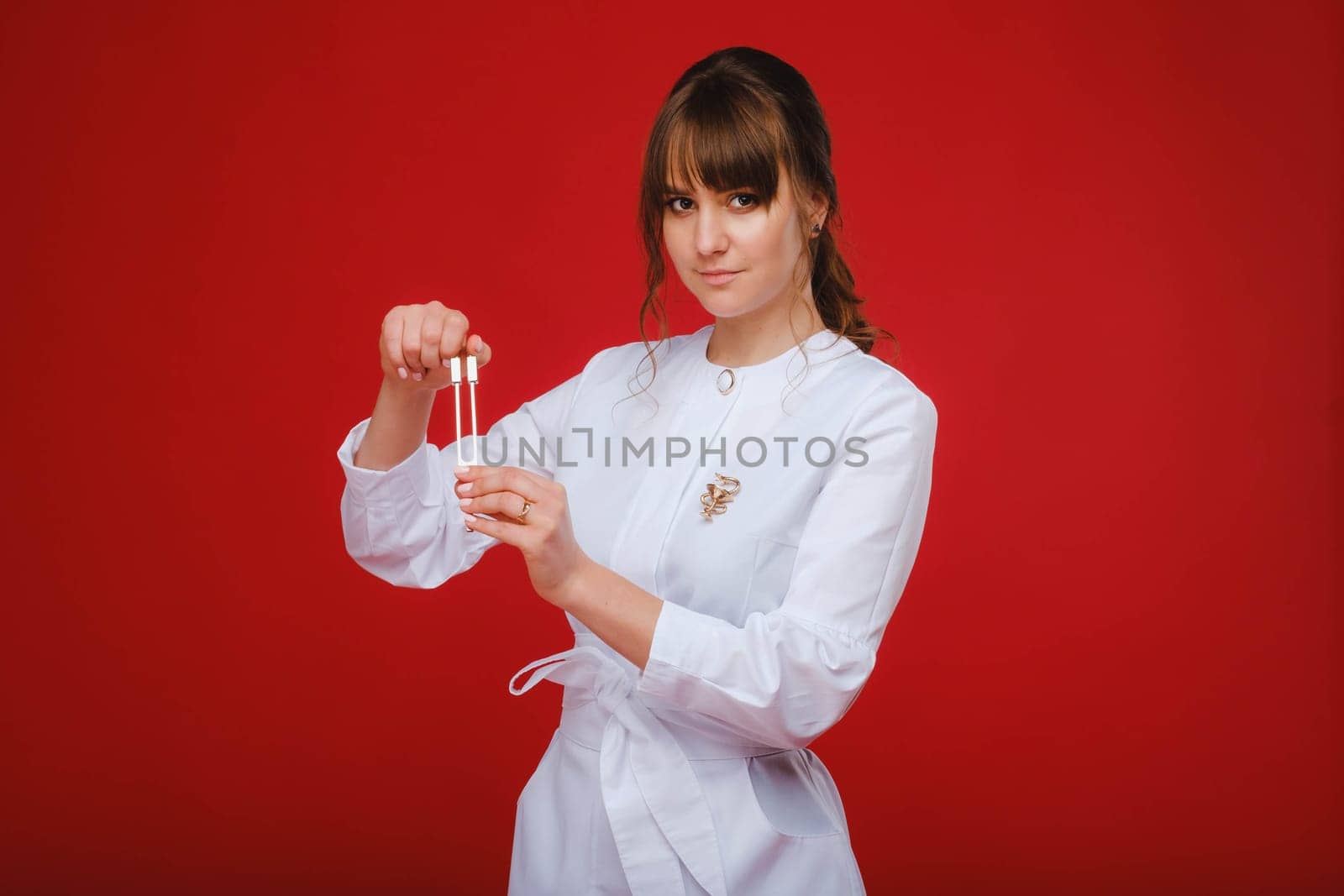 Beautiful girl doctor with a tuning fork stands.