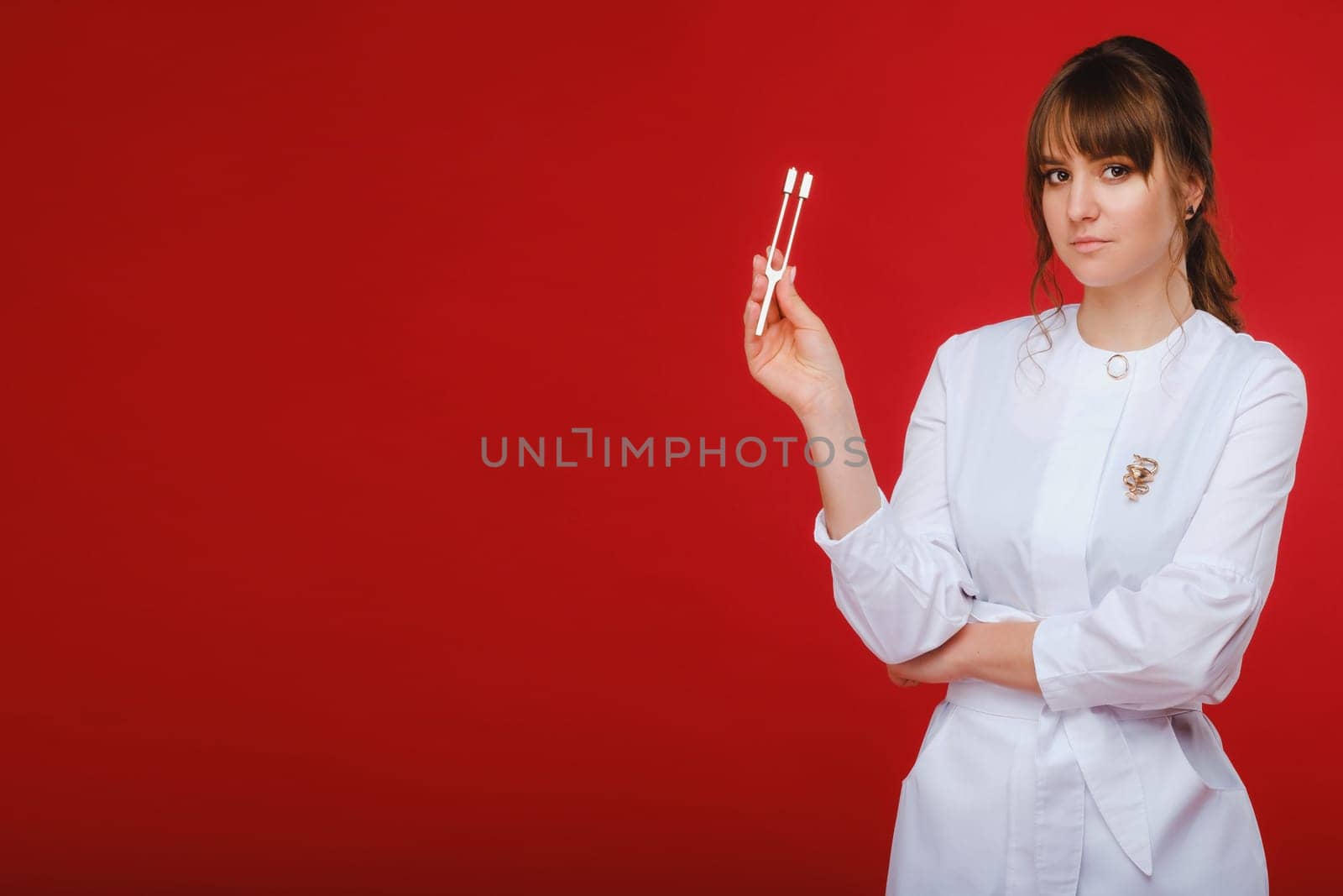 Beautiful girl doctor with a tuning fork stands.