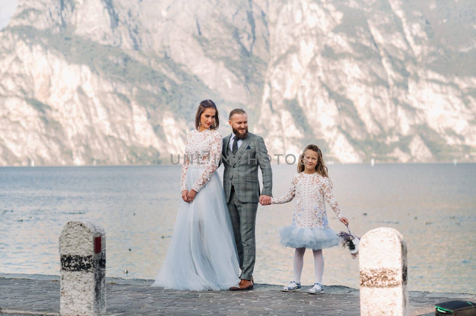 Italy, Lake Garda. Beautiful family on the shores of lake Garda in Italy at the foot of the Alps. Father, mother and daughter in Italy by Lobachad