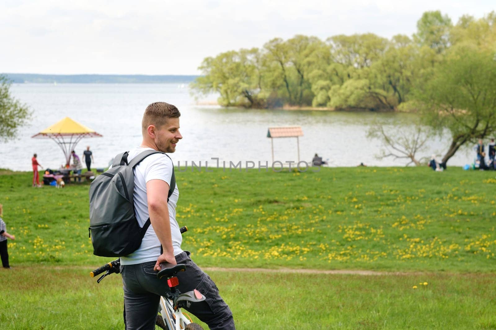 A cyclist with a backpack is standing on a bicycle in a clearing enjoying nature.