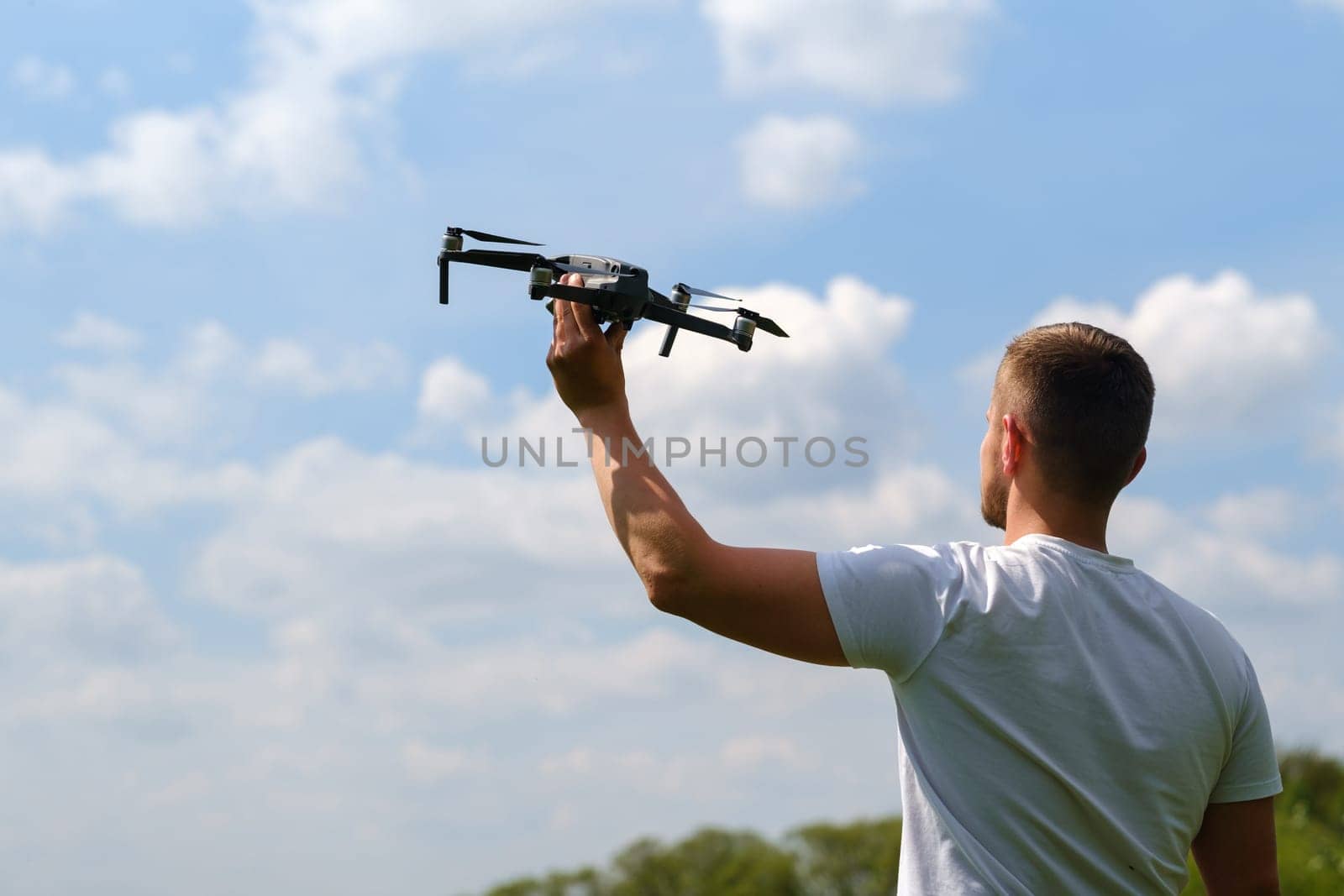 A man with a flying vehicle in his hands, raised to the sky in nature.Launching a drone.