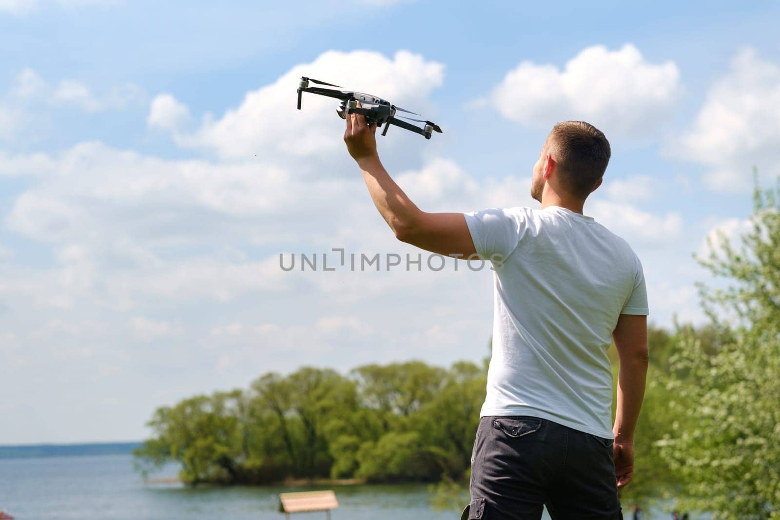 A man with a flying vehicle in his hands, raised to the sky in nature.Launching a drone by Lobachad