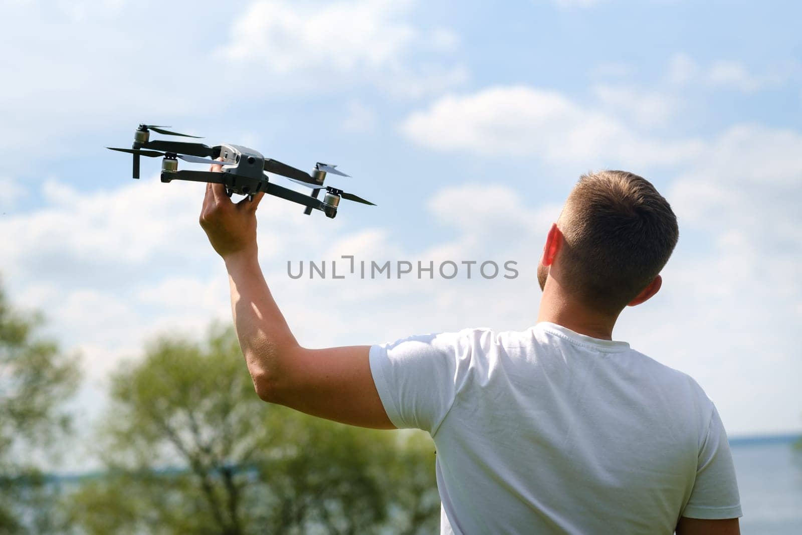 A man with a flying vehicle in his hands, raised to the sky in nature.Launching a drone.