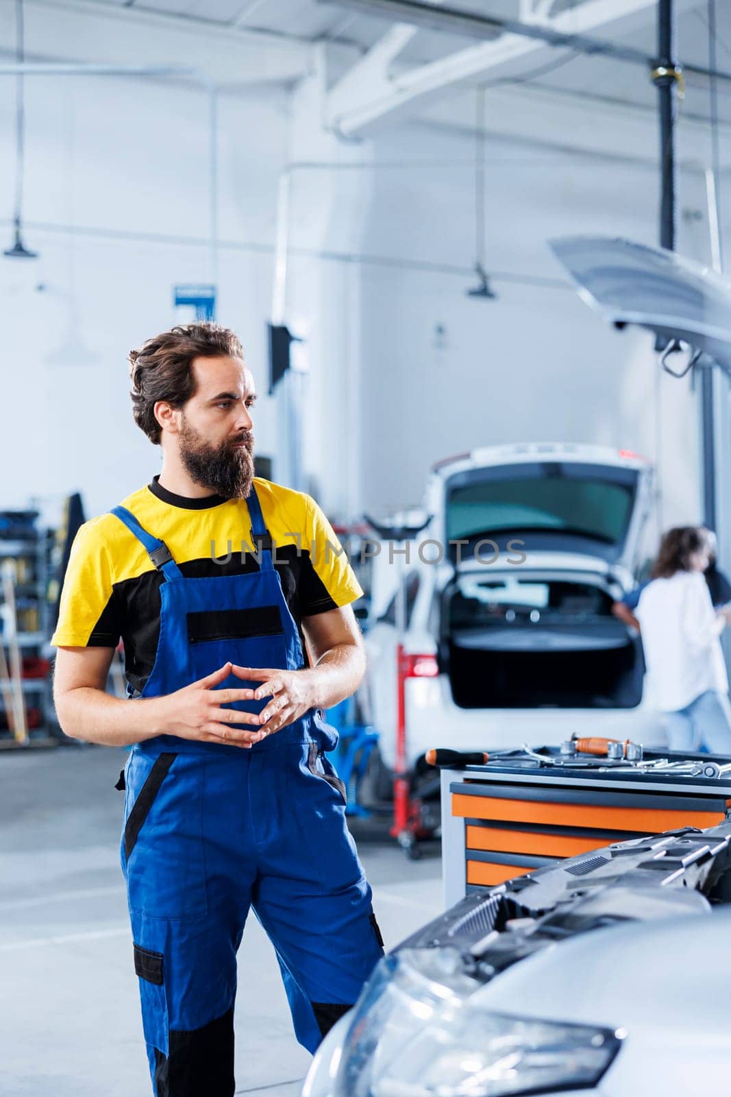 Engineer in repair shop using augmented reality holograms to check car specifications during checkup. Meticulous garage employee using futuristic AR technology to examine defective vehicle