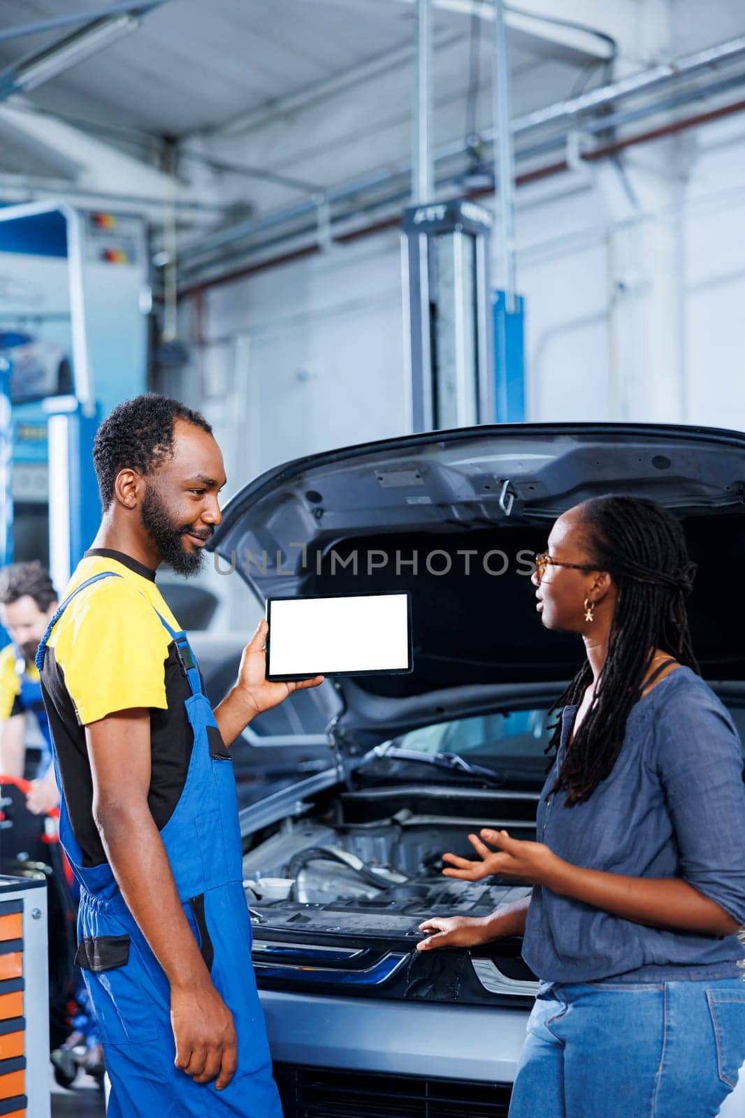 Licensed mechanic in car service uses mockup tablet to order new exhaust pipes for defective vehicle. Happy garage professional shows client needed components replacement on isolated screen device