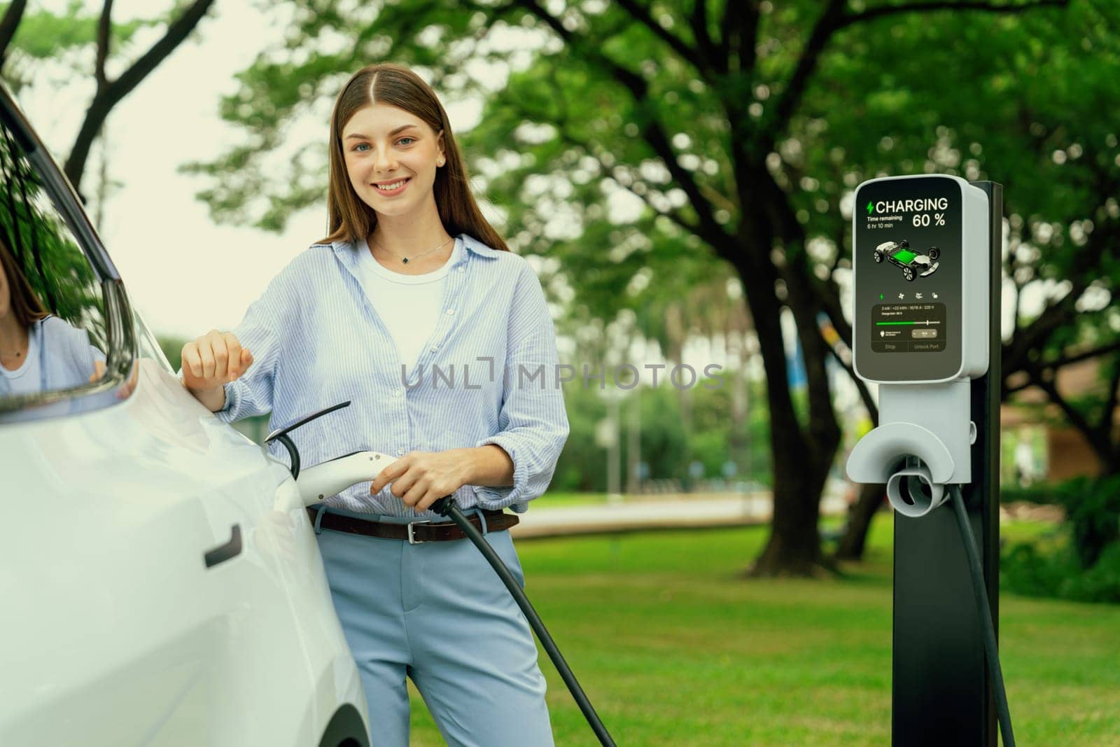 Young woman recharge EV electric vehicle battery from EV charging station. Exalt by biancoblue