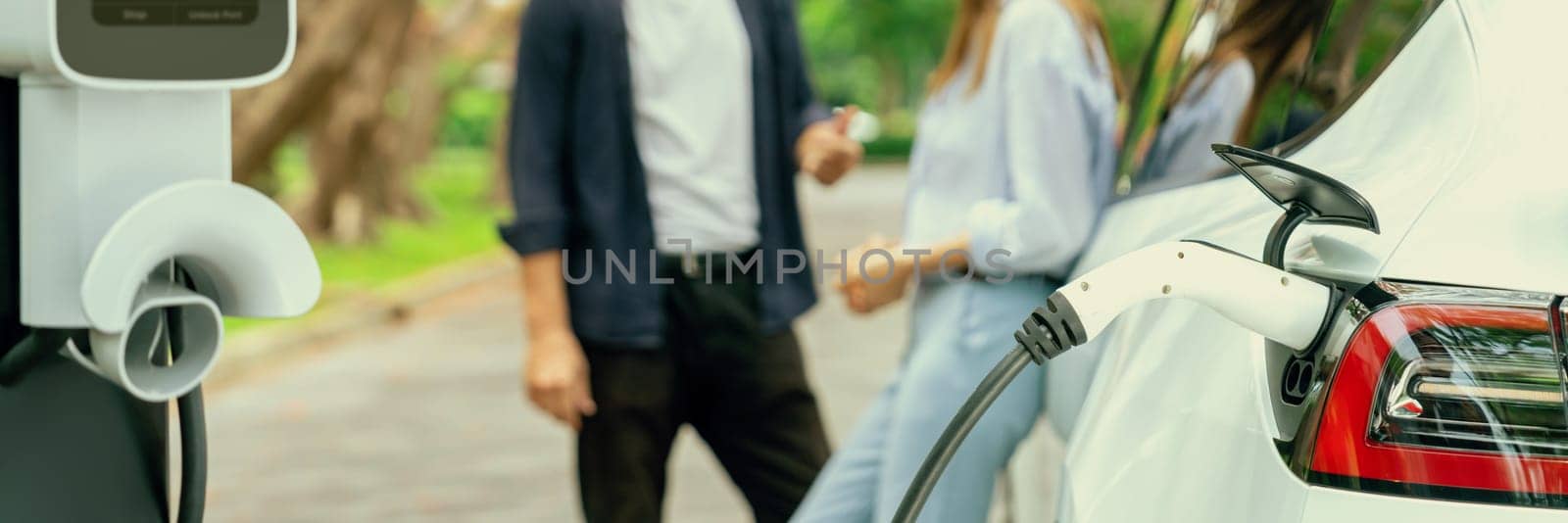 EV car recharging battery on blur background of lovely couple in autumn, Exalt by biancoblue