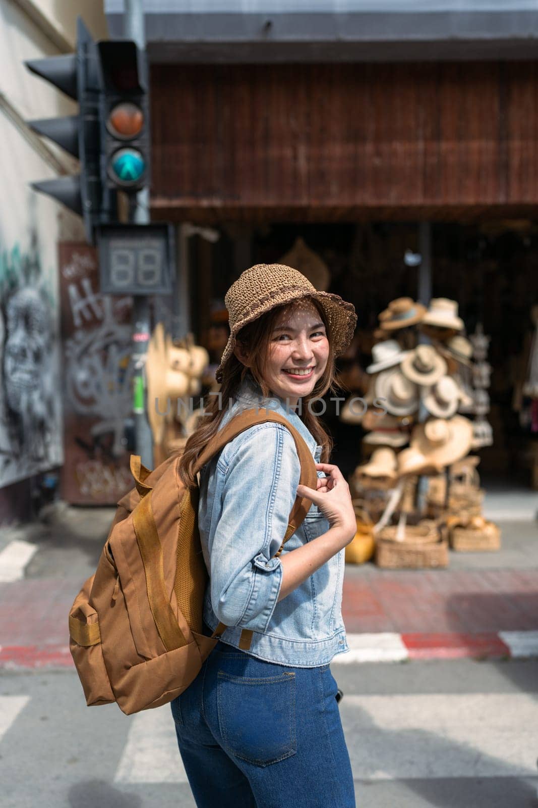 Young female tourist walking across the street and looking at camera while traveling in local market.