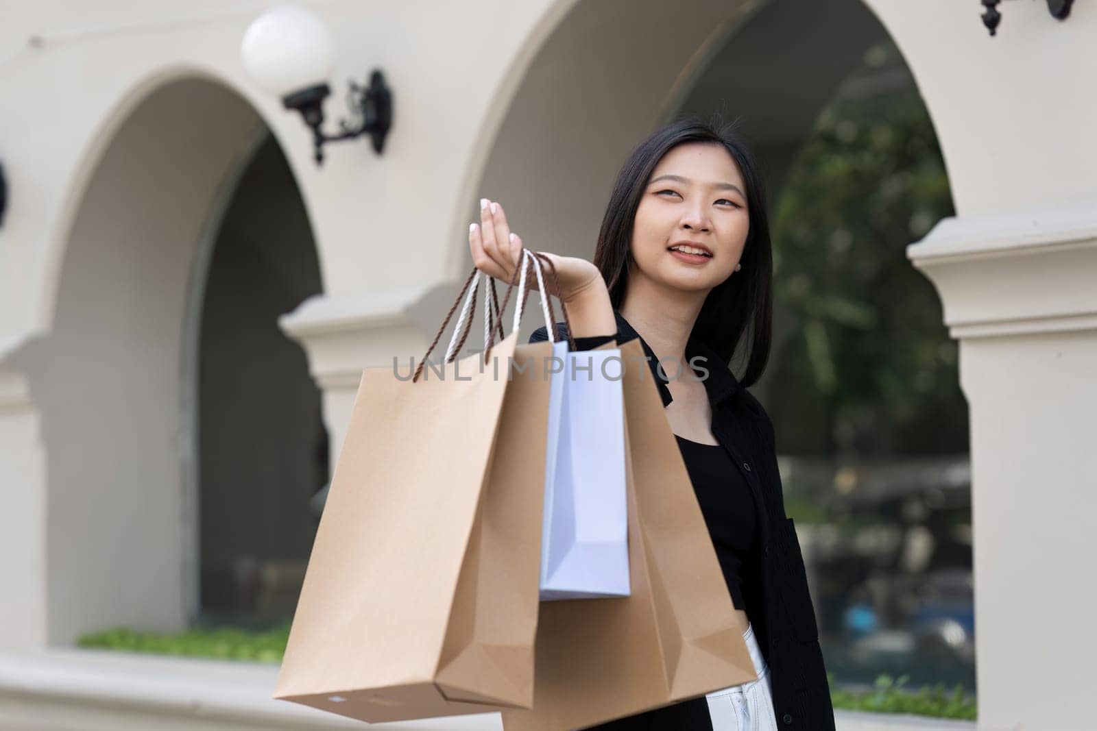 Young asian woman in shopping. Fashion woman in black with shopping bag walking around the city after shopping. Black friday by itchaznong