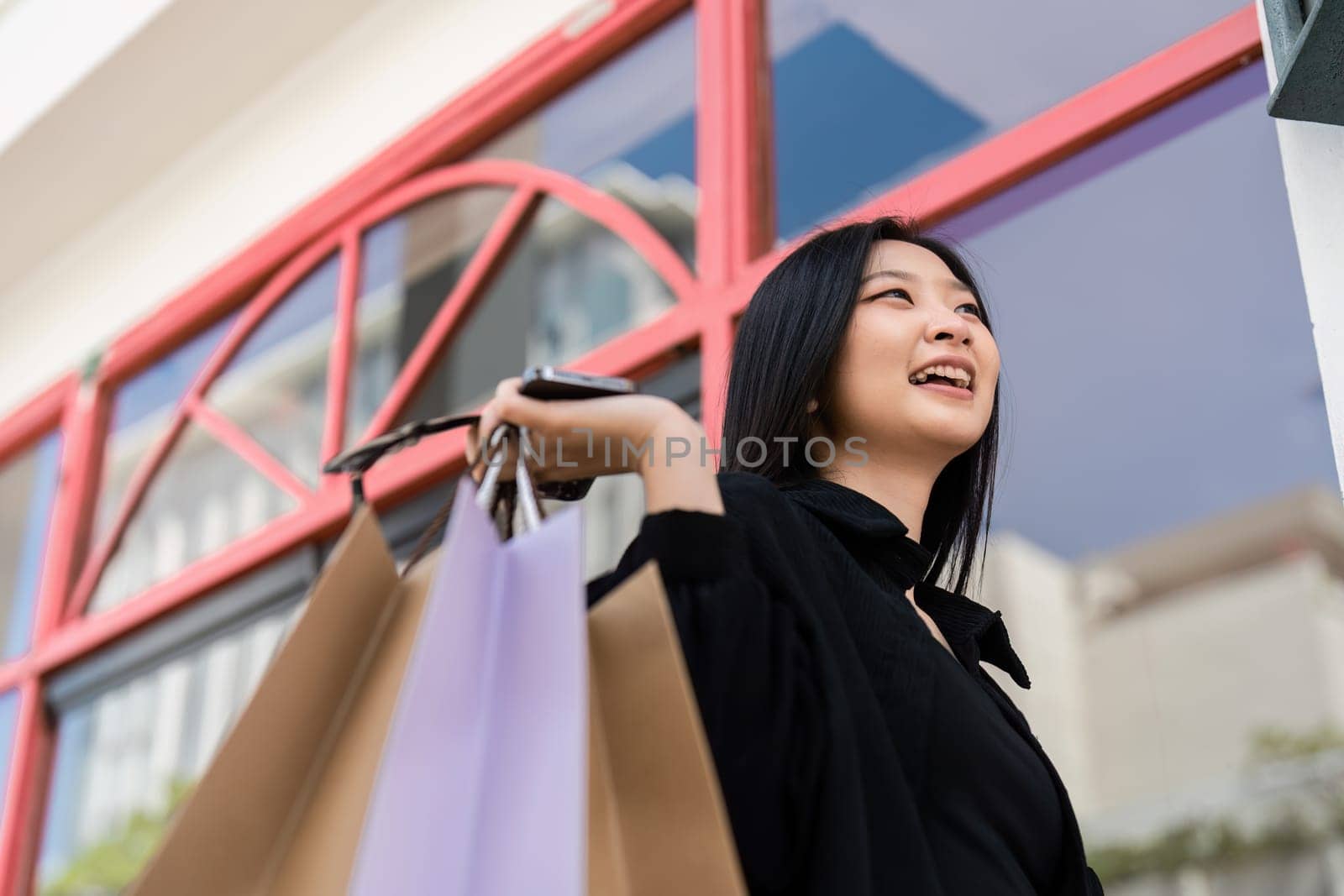Young asian woman in shopping. Fashion woman in black with shopping bag walking around the city after shopping. Black friday by itchaznong