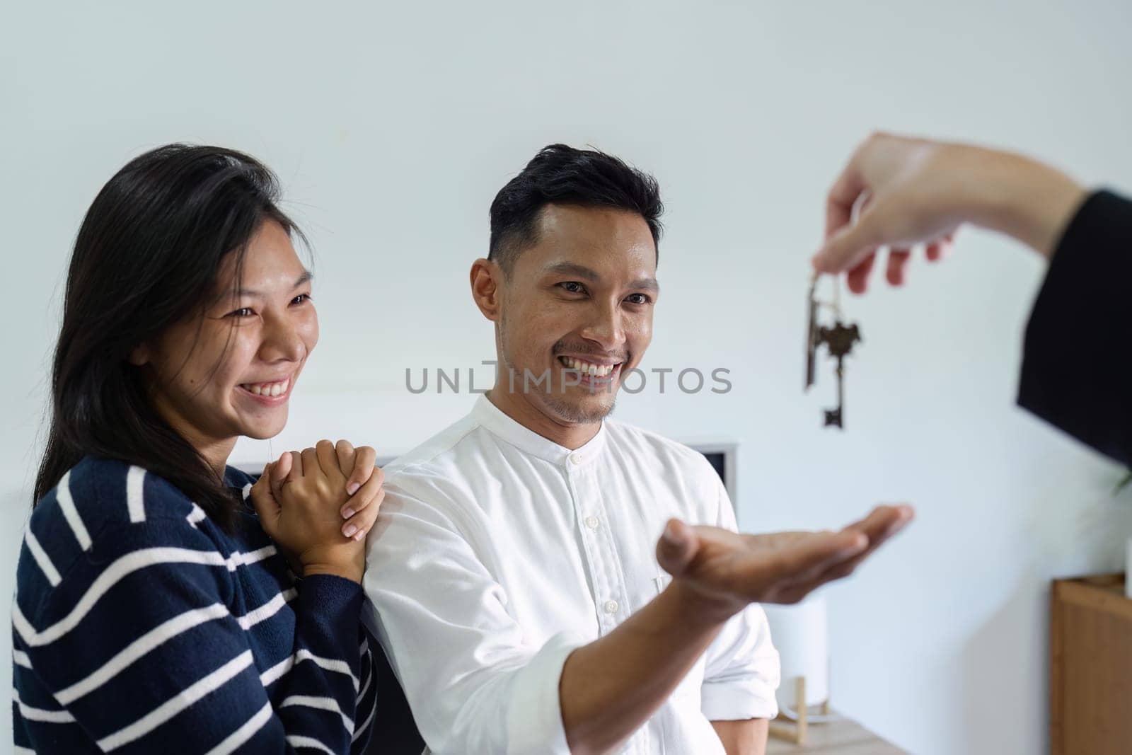 Happy real state agent giving new house key to a young couple. Real estate concept by itchaznong