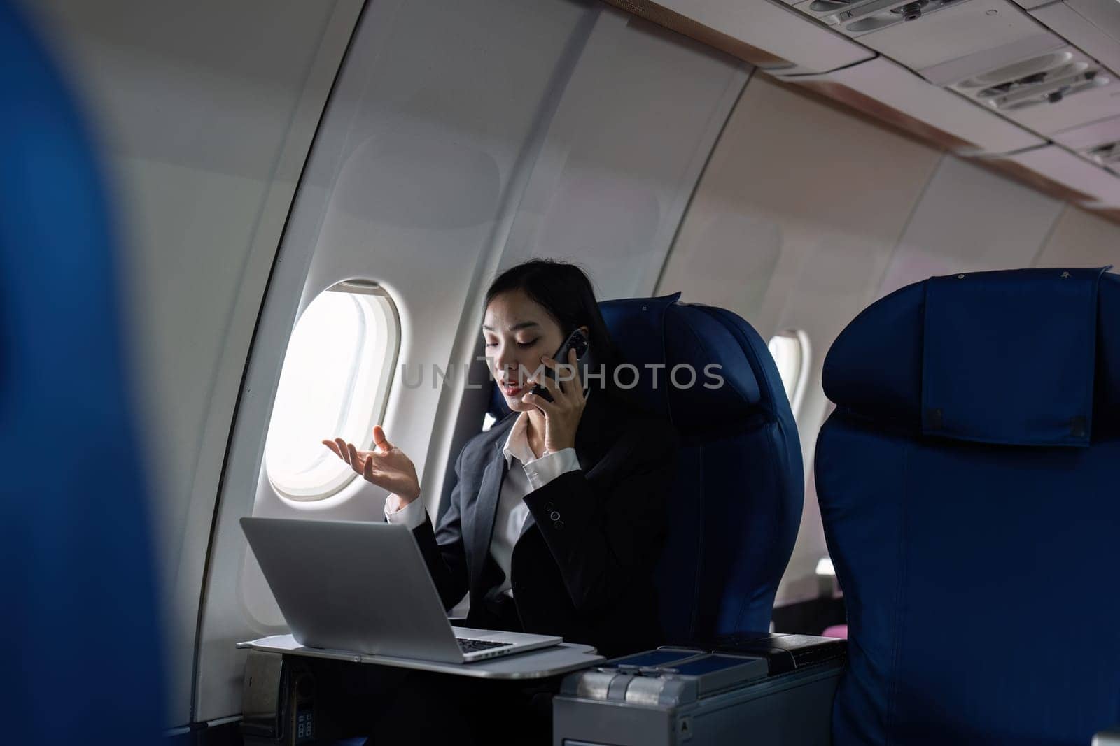 Beautiful Asian businesswoman working with laptop and mobile in aeroplane. working, travel, business concept.
