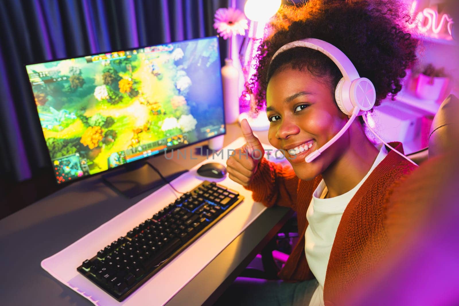 Host channel of gaming streamer, African girl playing fighting Moba game with joystick, wearing pastel headsets with mic, looking at the camera against background in neon color room. Tastemaker.