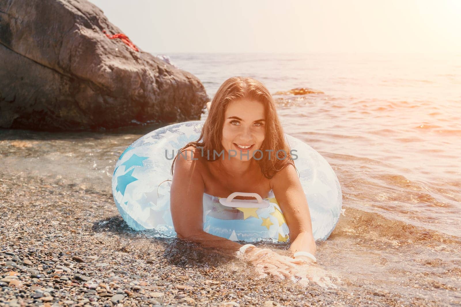 Woman summer sea. Happy woman swimming with inflatable donut on the beach in summer sunny day, surrounded by volcanic mountains. Summer vacation concept. by panophotograph