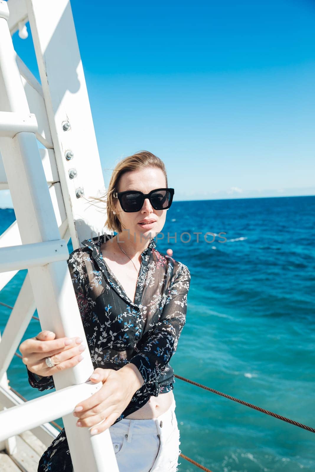 A woman wearing sunglasses near a rescue tower by the sea
