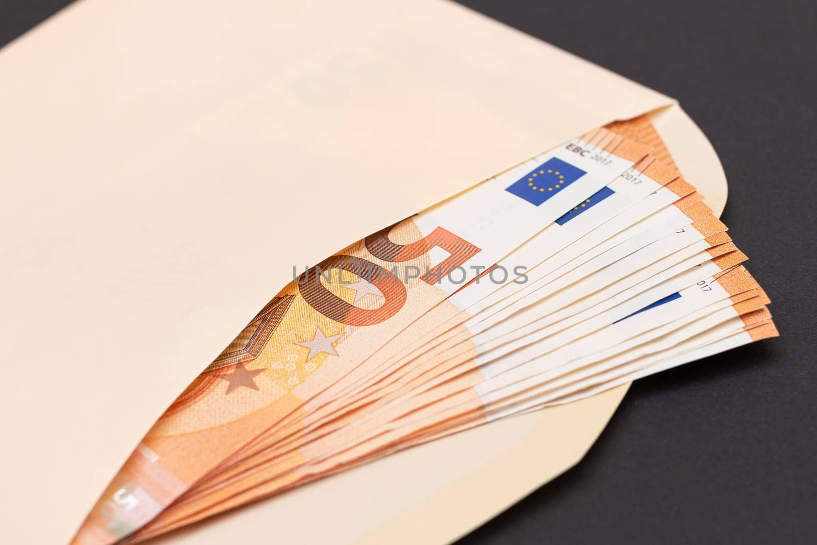 An Orange Paper Envelope with Stack of 50-Euro Banknotes Inside. Salary in Cash. Tax-Free System. Euro Currency. Payments with No Taxes. Orange Paper Money. A Lot of Fifty-Euro Bills