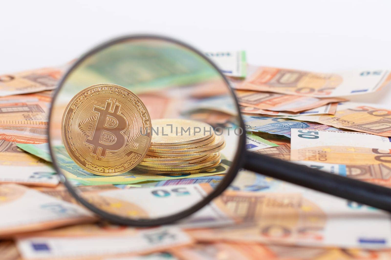 A Stack of Bitcoin Coins Visible Through a Magnifying Glass on the 50-Euro Banknotes. Euro Currency and Crypto Currency. Orange Paper Money. A Lot of Fifty-Euro Bills. Anonymous Payments Concept