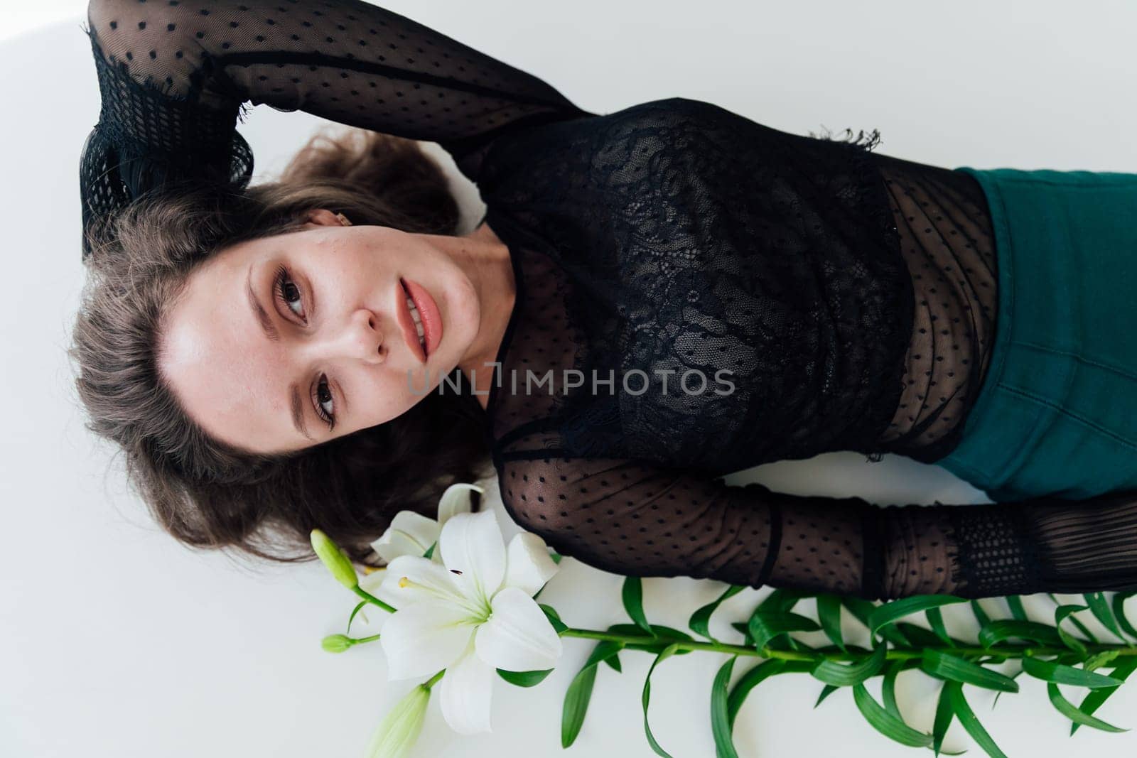 Brunette lying on the floor with lily flowers in a bright room