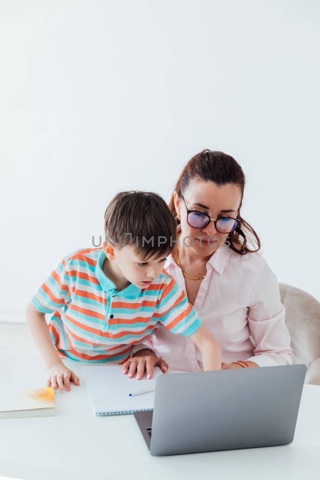 Woman with boy playing laptop online by Simakov