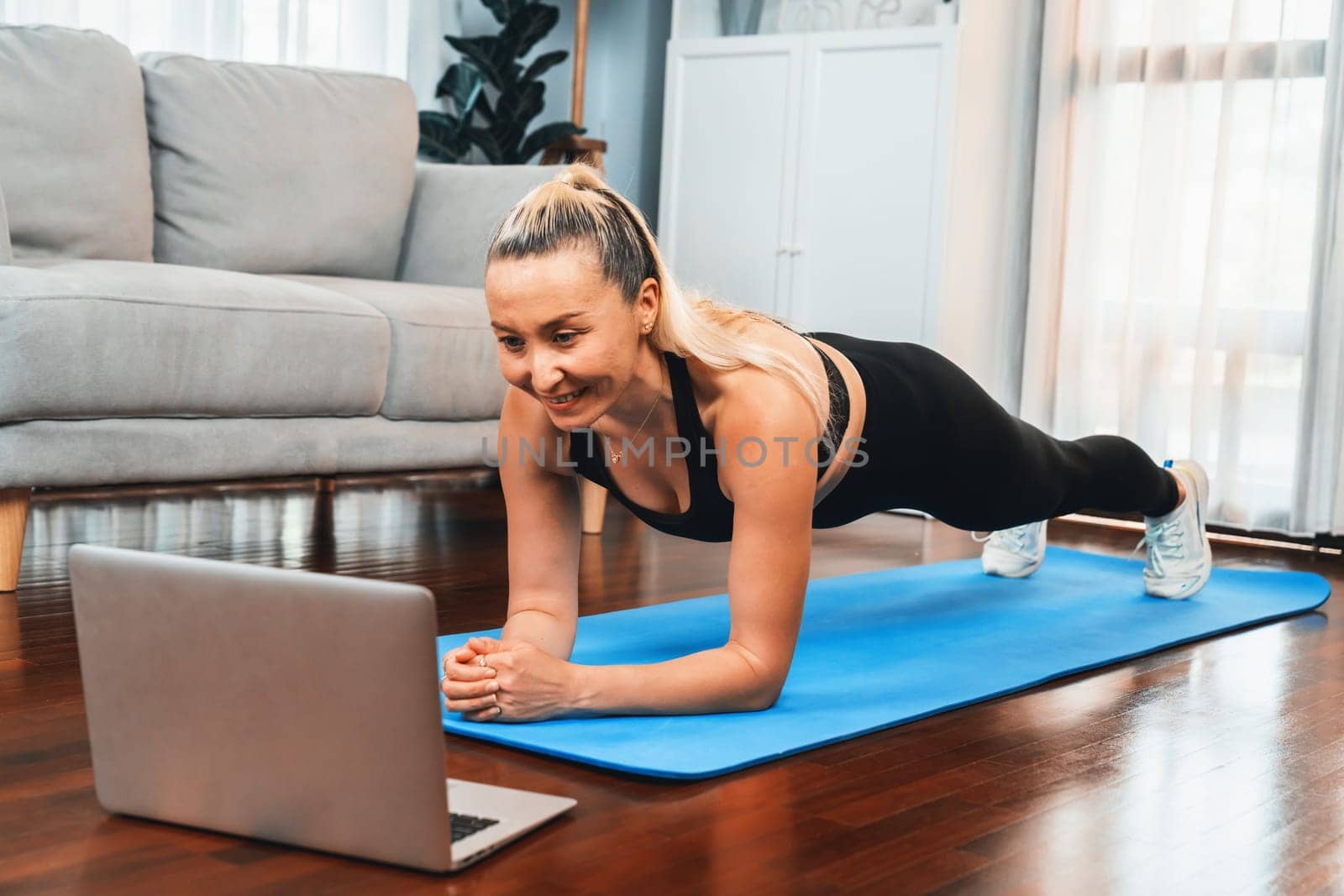 Athletic and sporty senior woman planking on fitness exercising mat while watching online fitness video at home exercise as concept of healthy fit body lifestyle after retirement. Clout