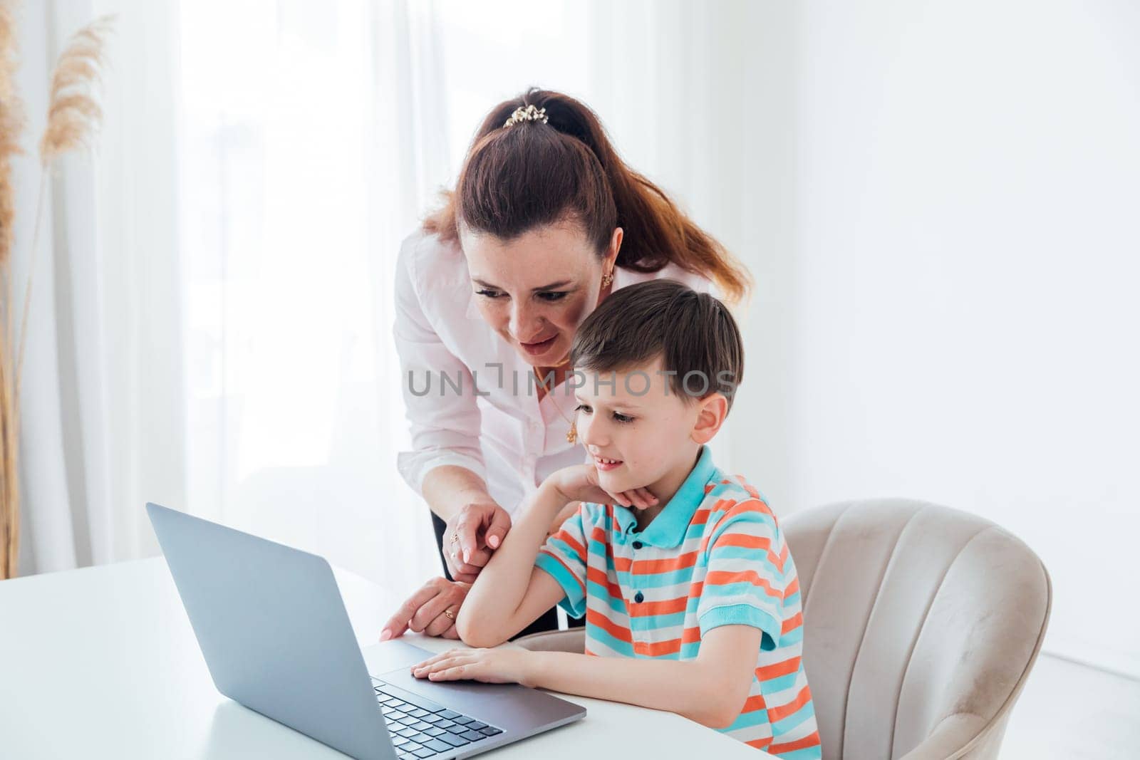 Mom helps her son do school assignment on computer