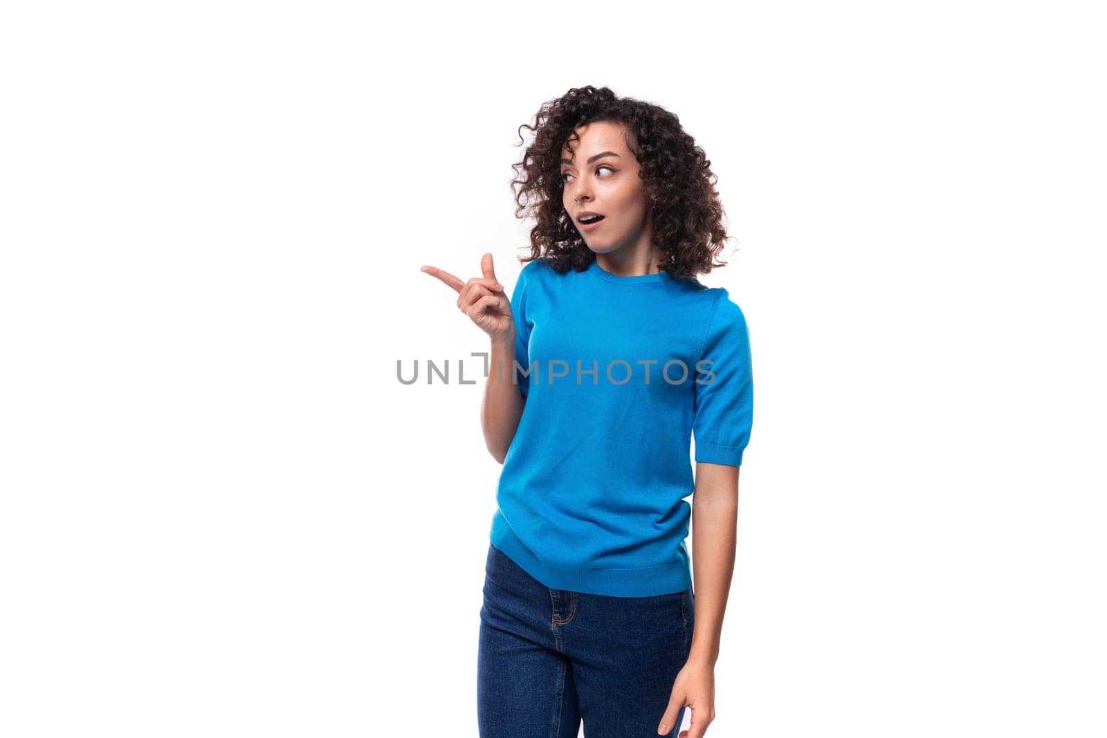 a bright curly woman dressed in a blue summer jacket actively gesticulates against the background with copy space. advertising concept.