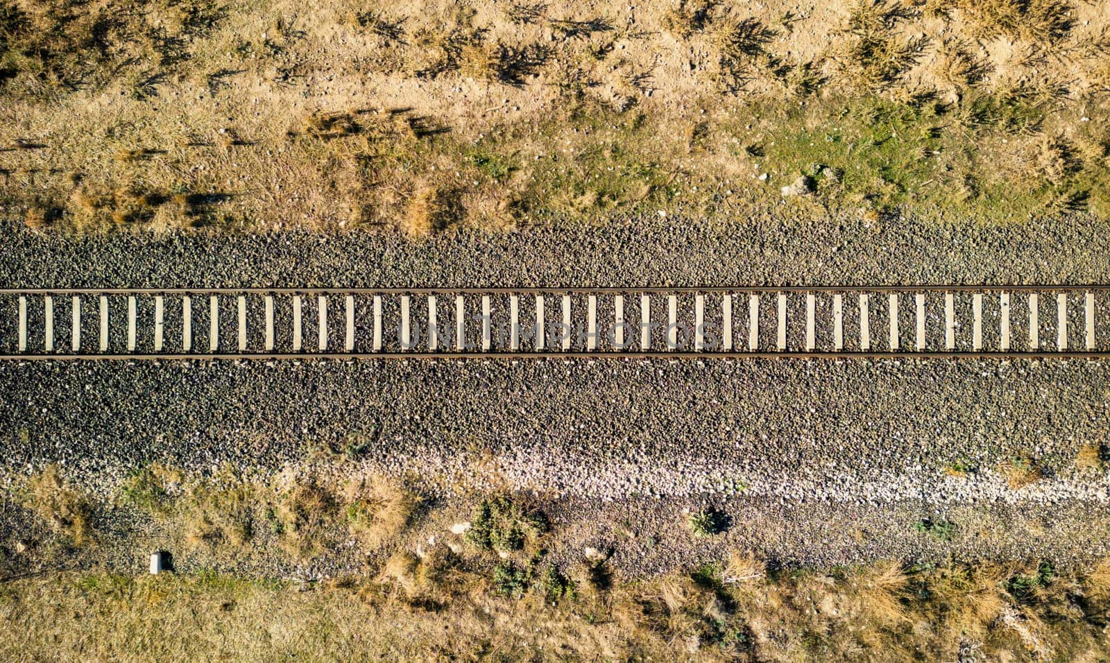 Top view of the train track passing through the arid land, taken with a drone by Sonat