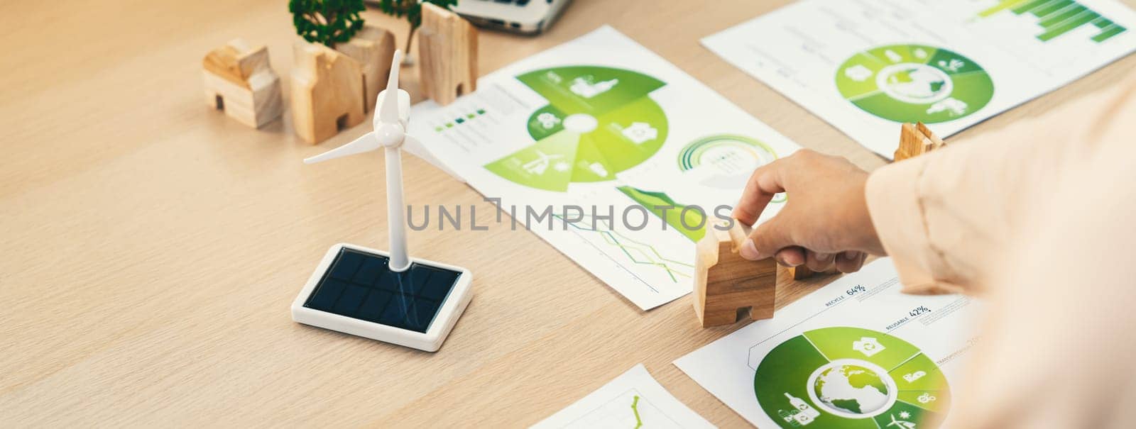 Environmental documents and a windmill model representing the use of clean energy are scattered on the table during a green business discussion about investing in clean energy. Closeup. Delineation.