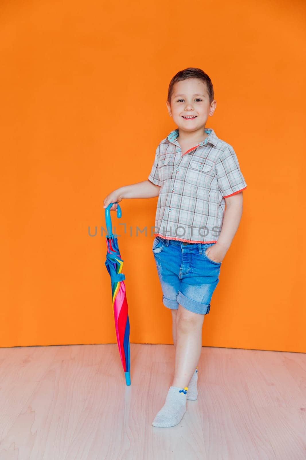 Little boy standing with colorful umbrella from the rain by Simakov