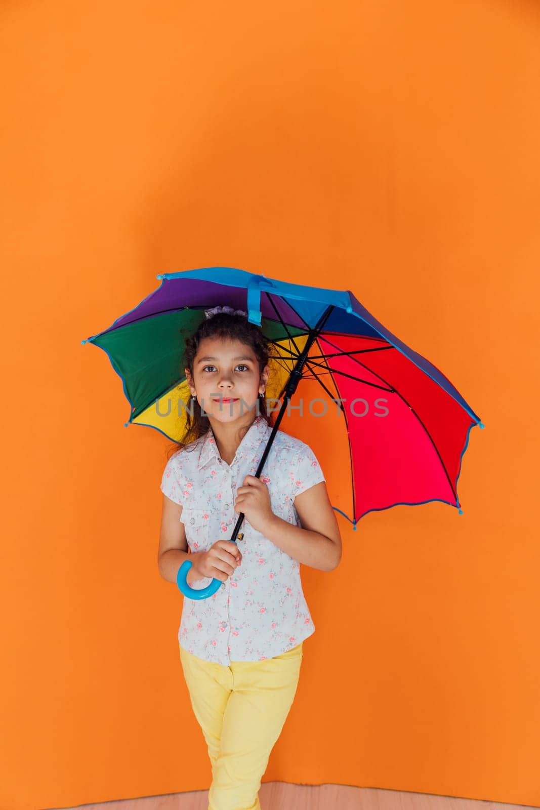 Little girl standing with colorful umbrella from the rain by Simakov