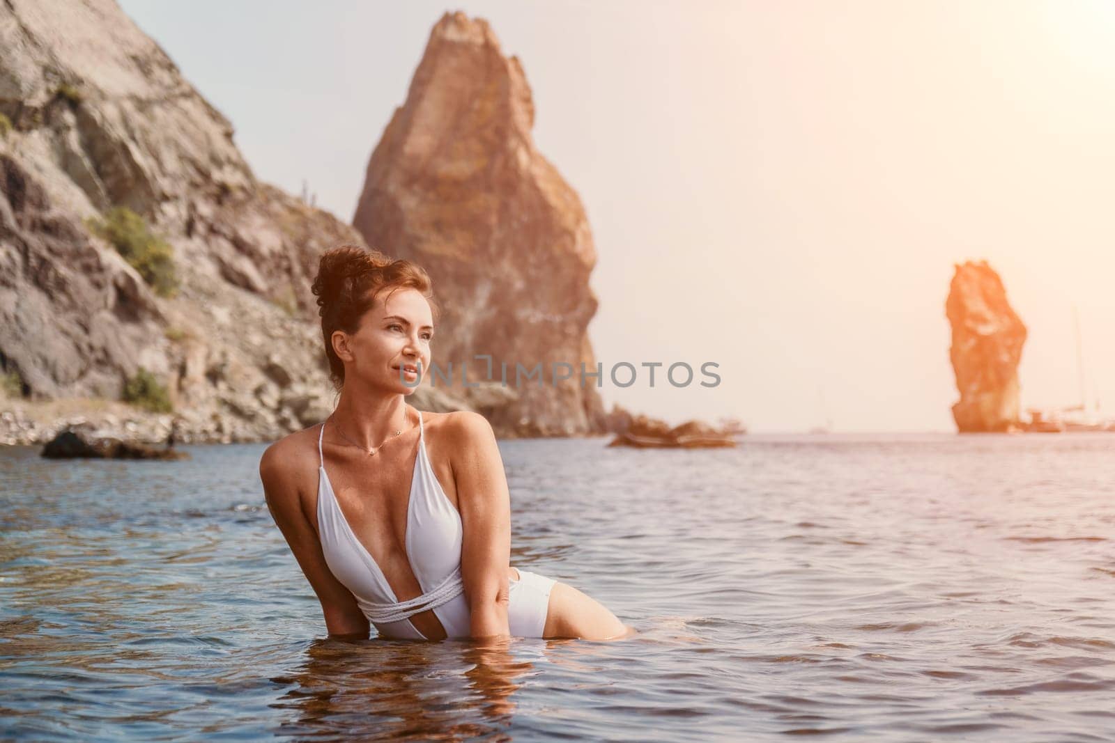 Woman sea fitness. Happy woman in a white bikini performing pilates in the sea on the beach. Female fitness yoga routine concept. Healthy lifestyle. by panophotograph