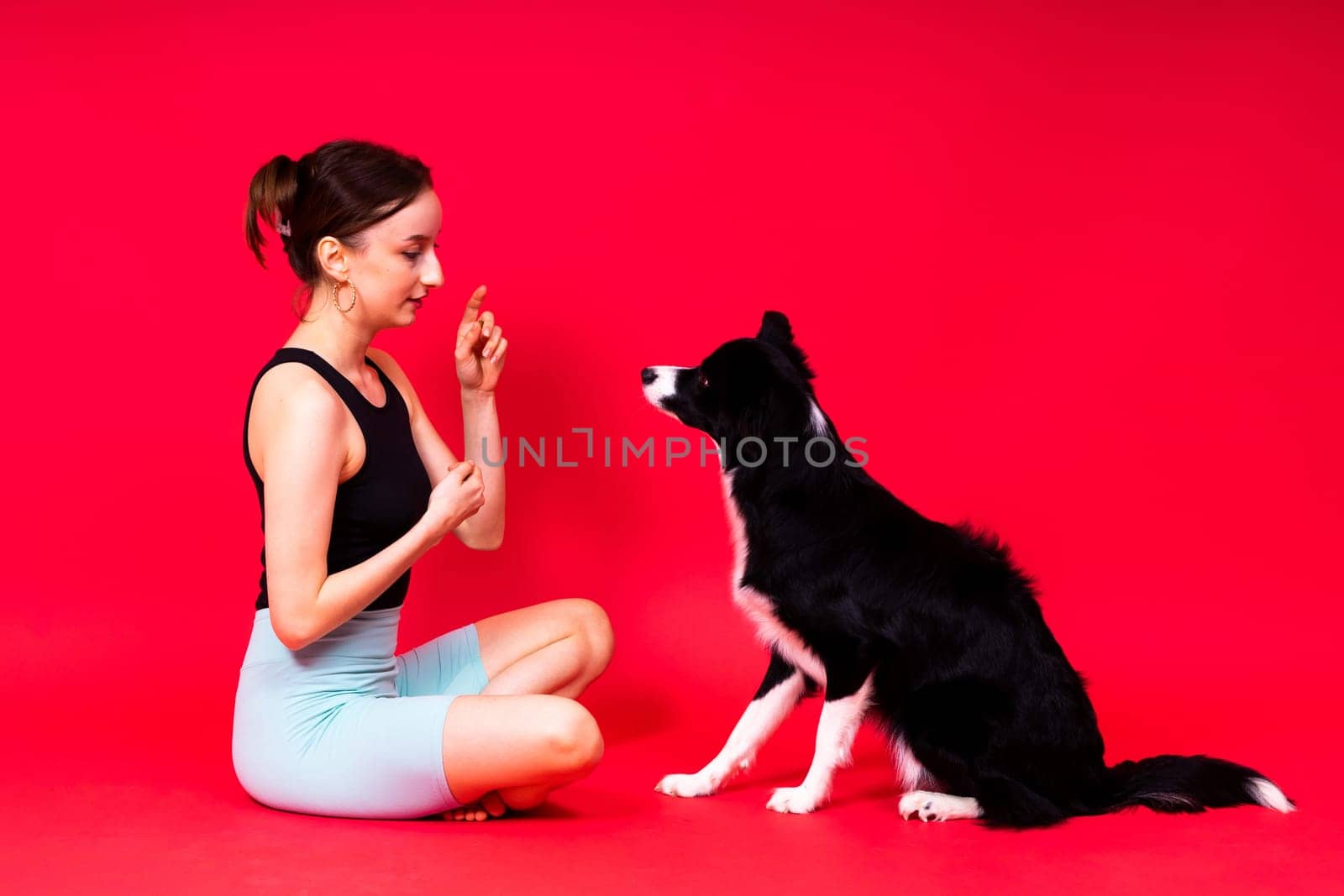 Shot of sport female in leggings with a border collie dog isolated on yellow and red background
