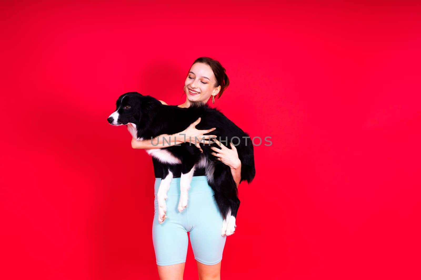 Shot of sport female in leggings with a border collie dog isolated on yellow and red background