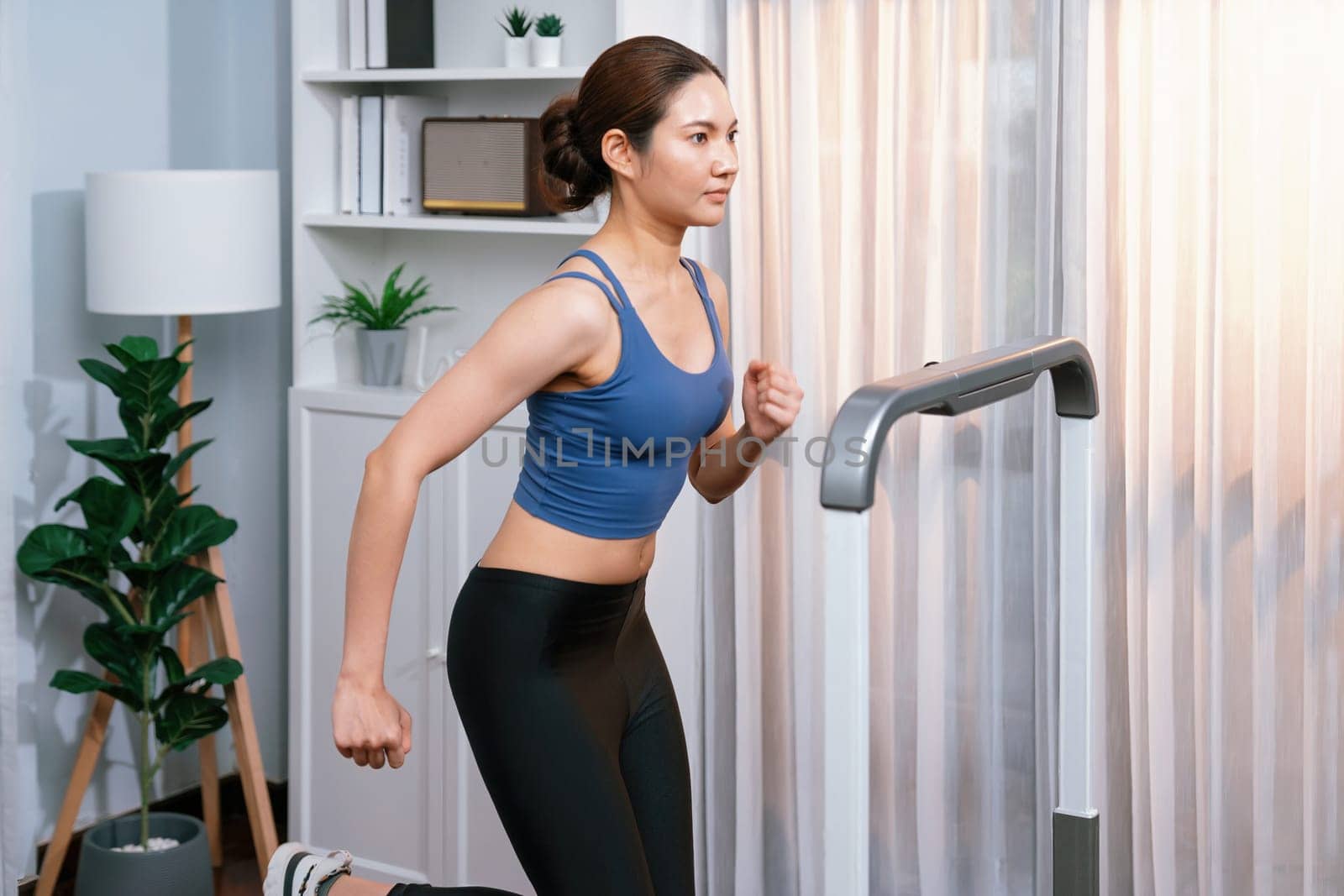 Energetic and strong athletic asian woman running at home. Vigorous by biancoblue