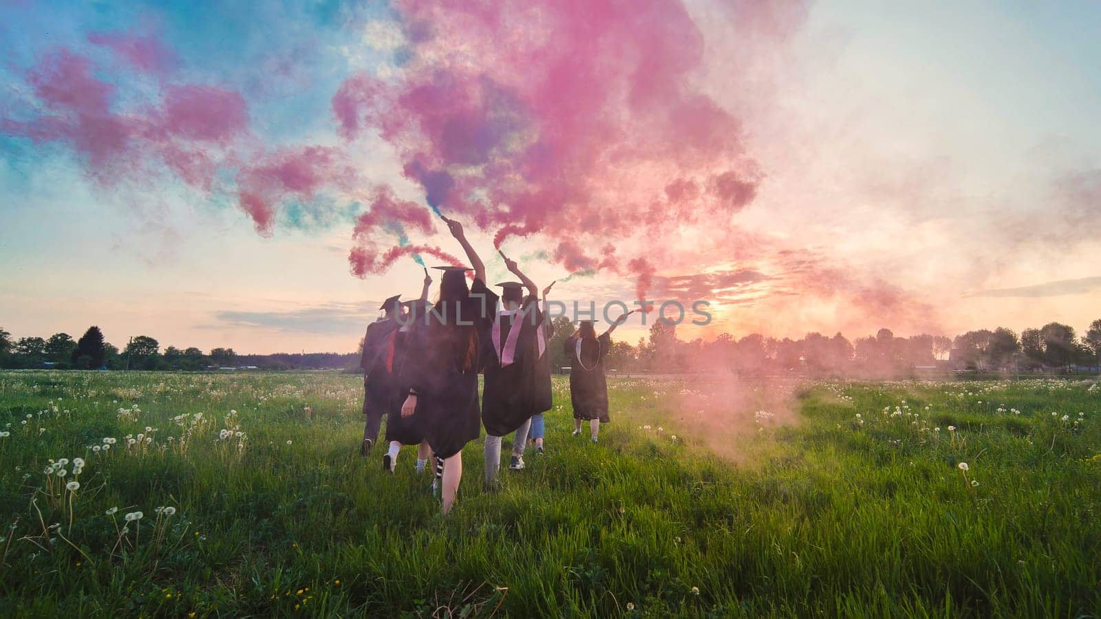 Graduates in costume walk with a smoky multi-colored smoke at sunset by DovidPro