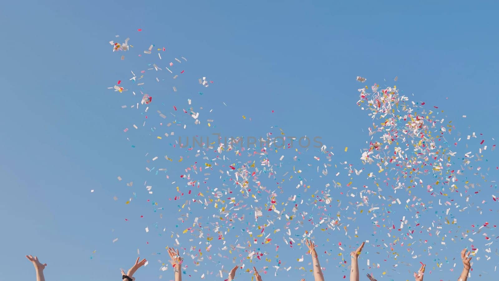 Tossing colorful paper confetti from the hands of young people