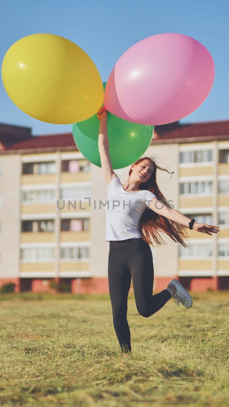 A girl happily poses with large with colorful balloons in the city. by DovidPro