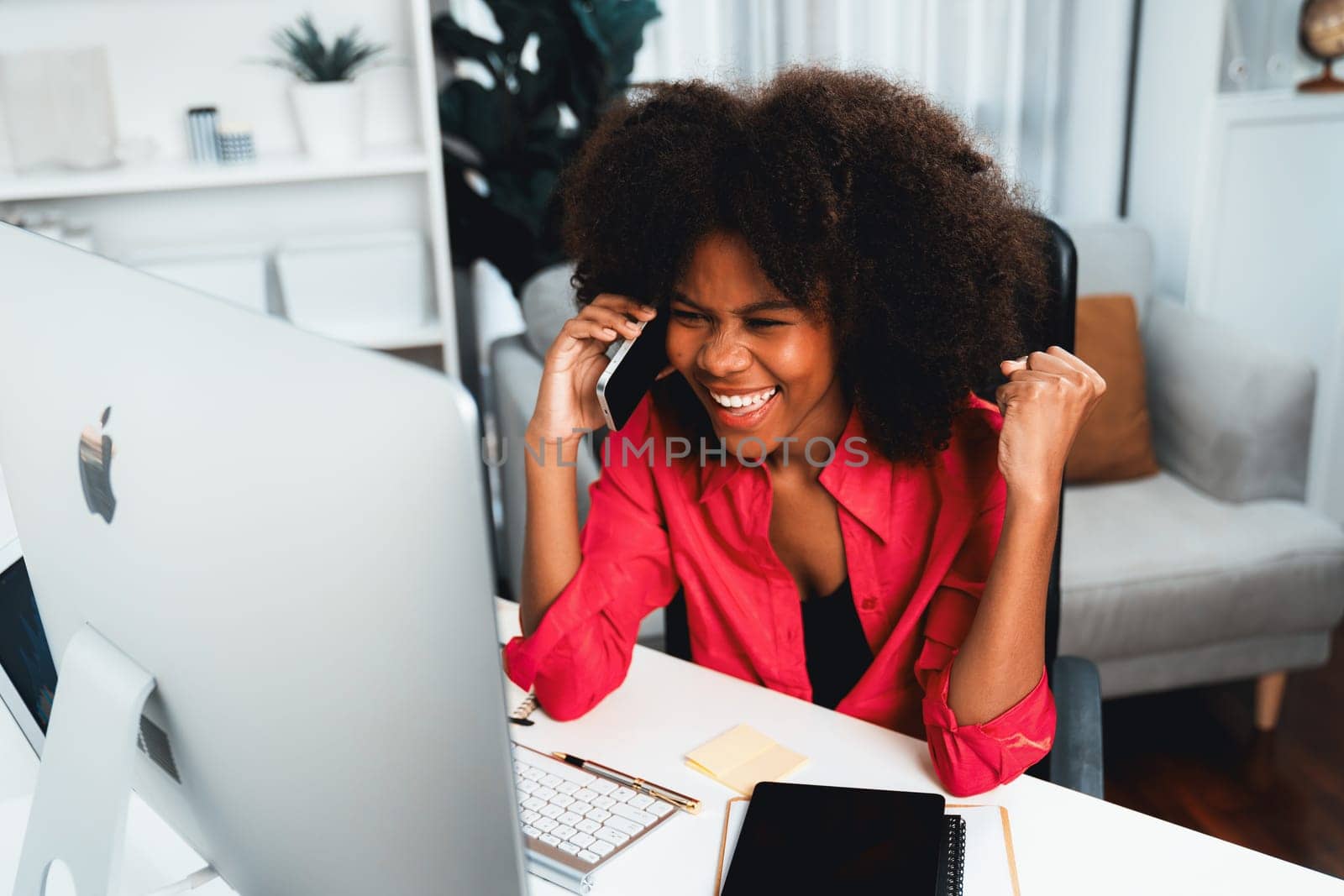 African woman talking with coworker or friend on the phone and looking at the screen with happy face. Achievement for promoting job position in the company with the good news life. Tastemaker.