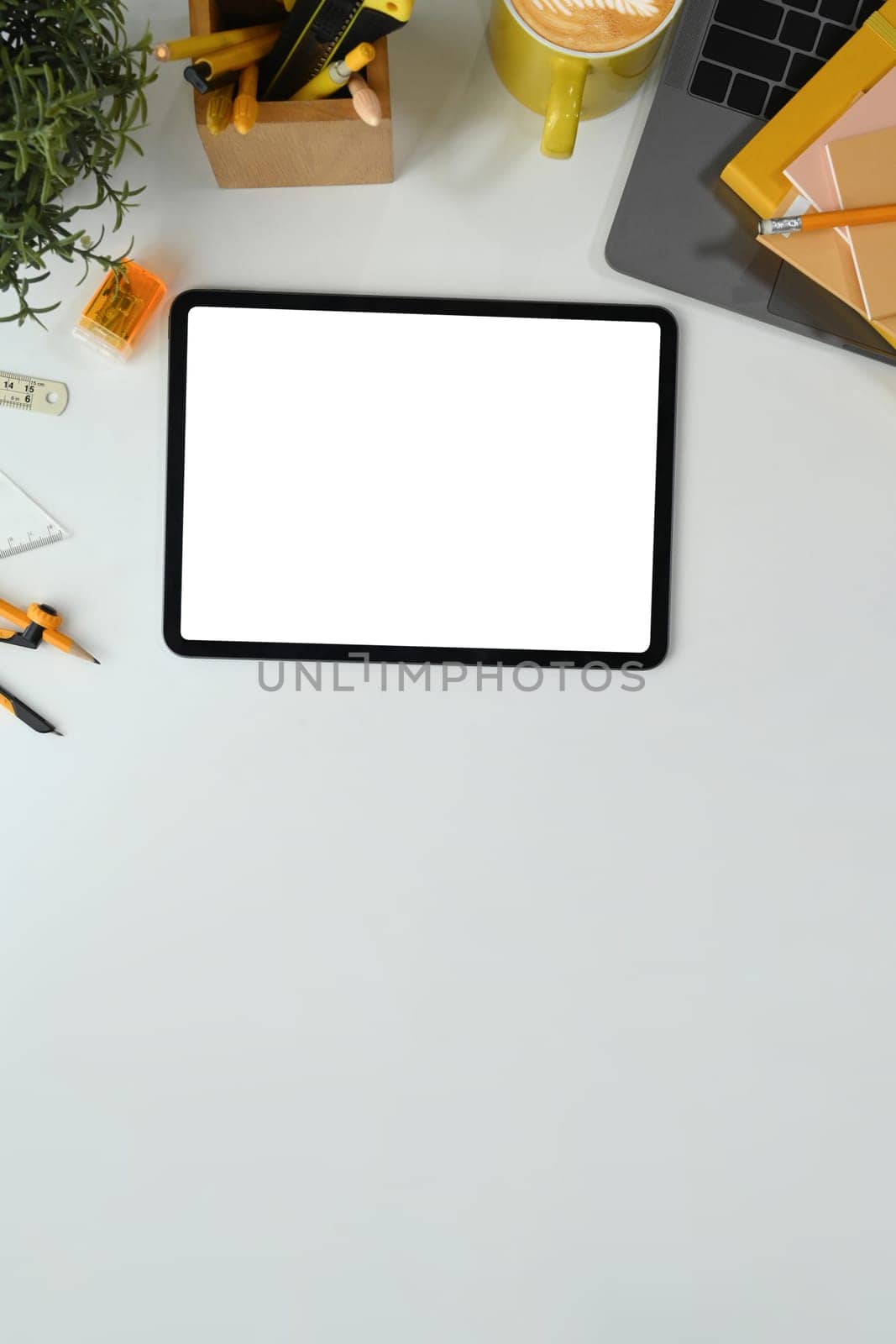 Flat lay, top view digital tablet with white empty screen, coffee cup and laptop on white table.