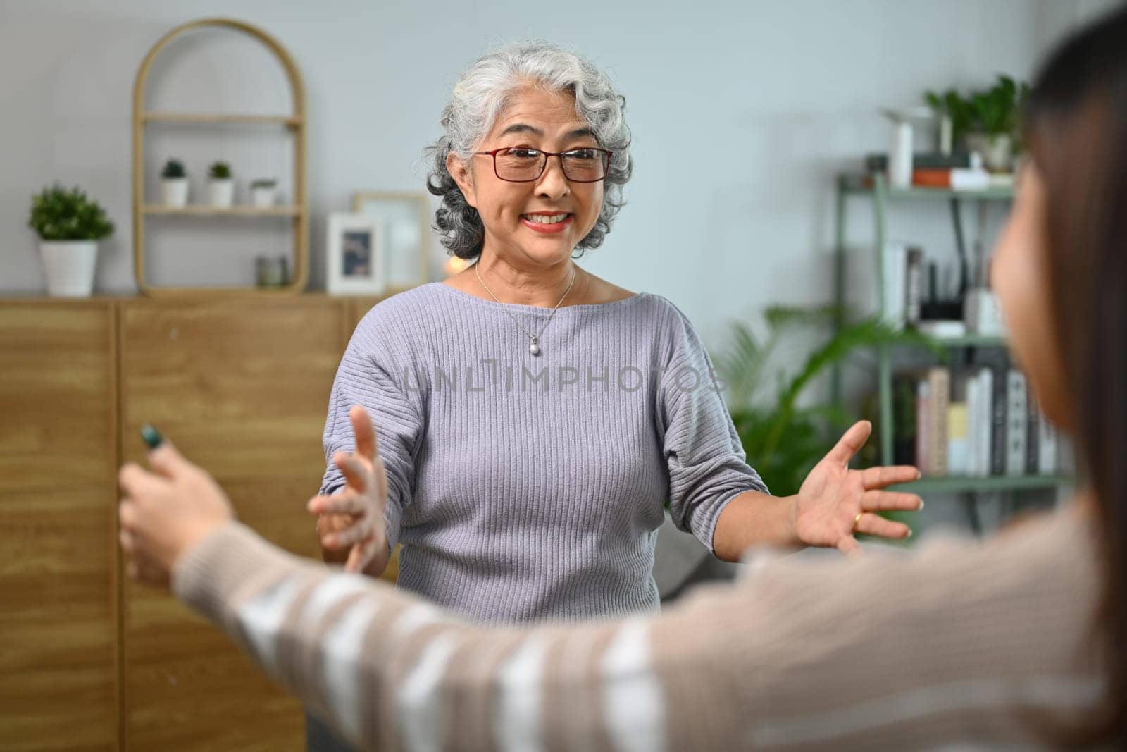 Happy excited senior mother opening her arm to hug her adult daughter. Happy family concept.