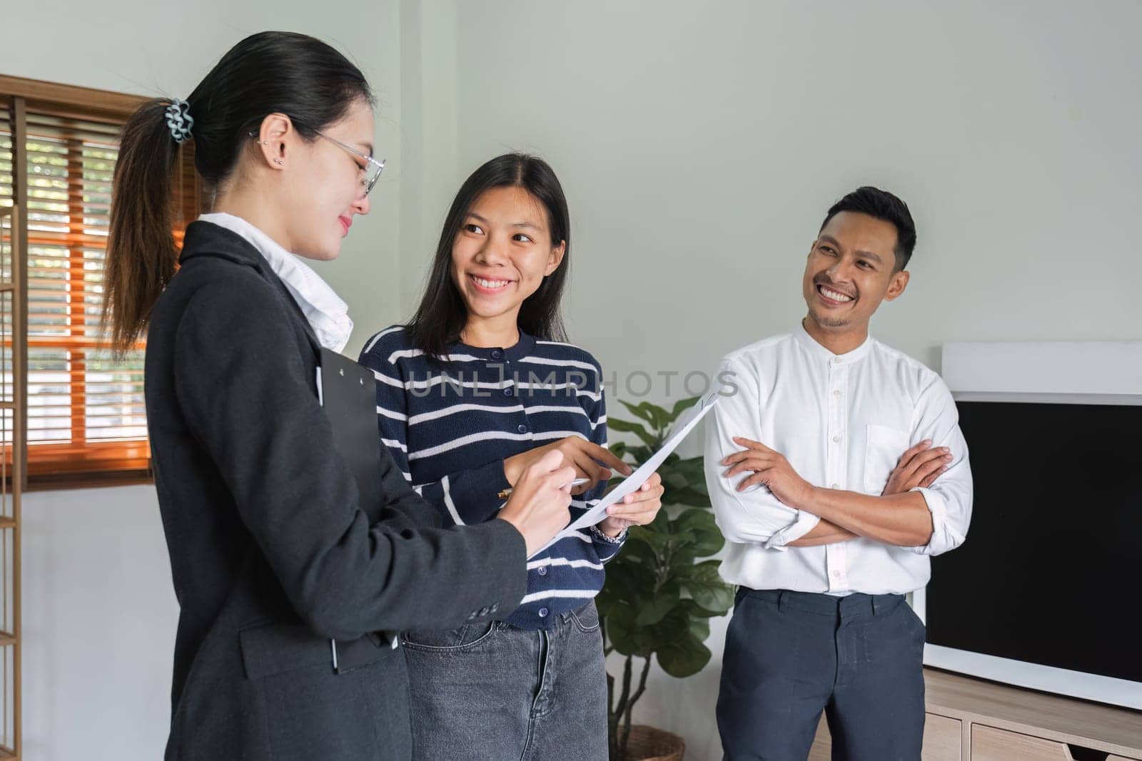 Real estate agents present and advise clients on the decision to sign a home purchase agreement form. Offering mortgage loans and home insurance.