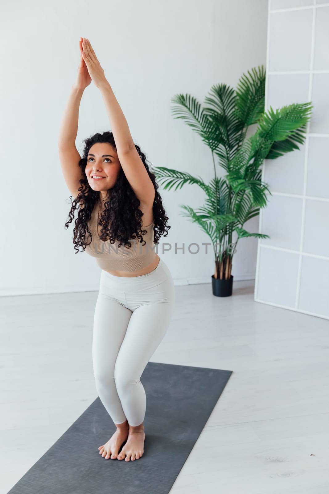 Gorgeous young woman practicing yoga indoor. Beautiful girl practice adkho-mukkha-shvanasana in a training hall.Calmness and relax, female happiness concept.Vertical, blurred background