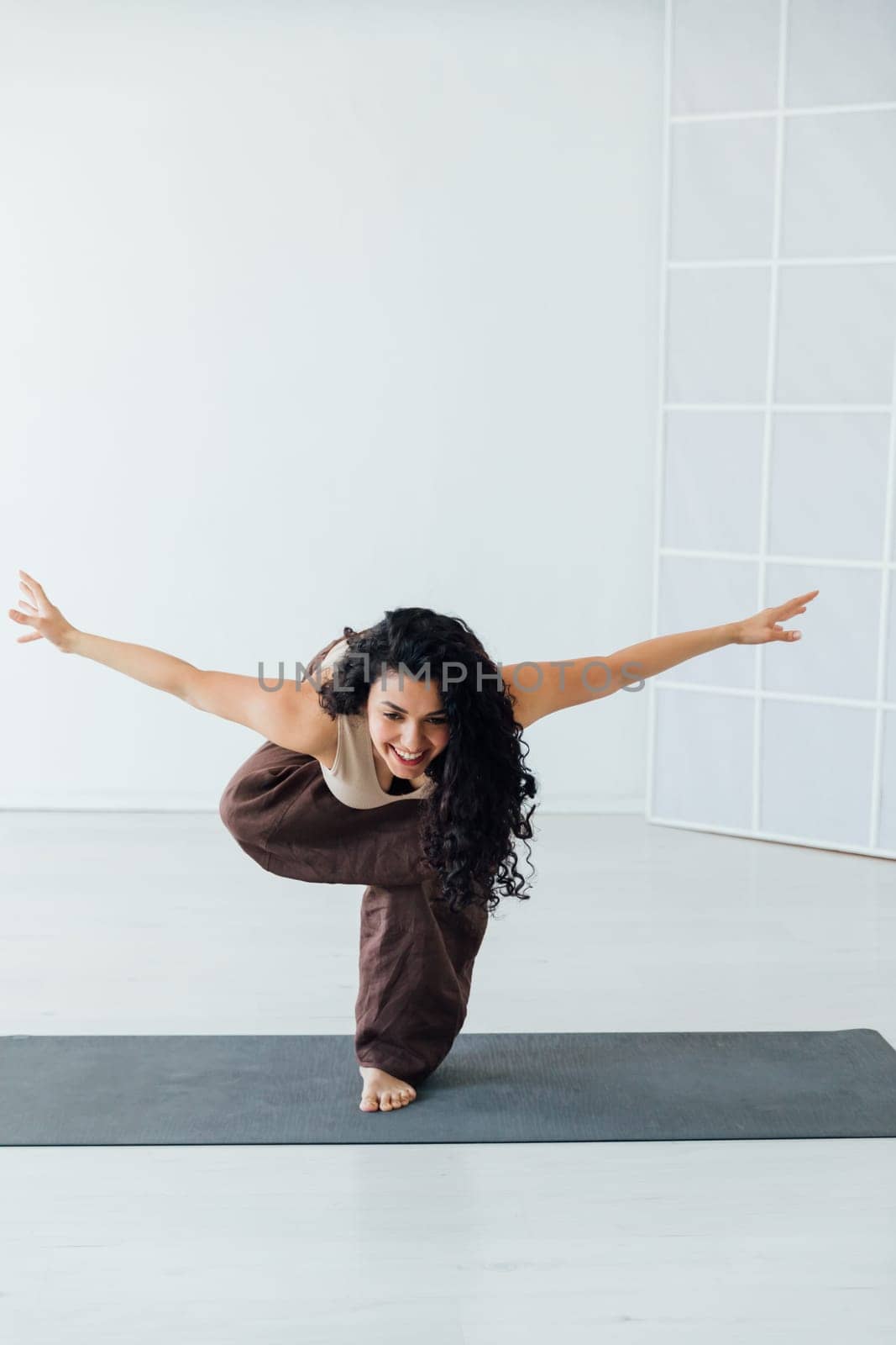 Fit healthy woman doing pilates yoga exercise fitness training workout at home interior standing in warrior pose.