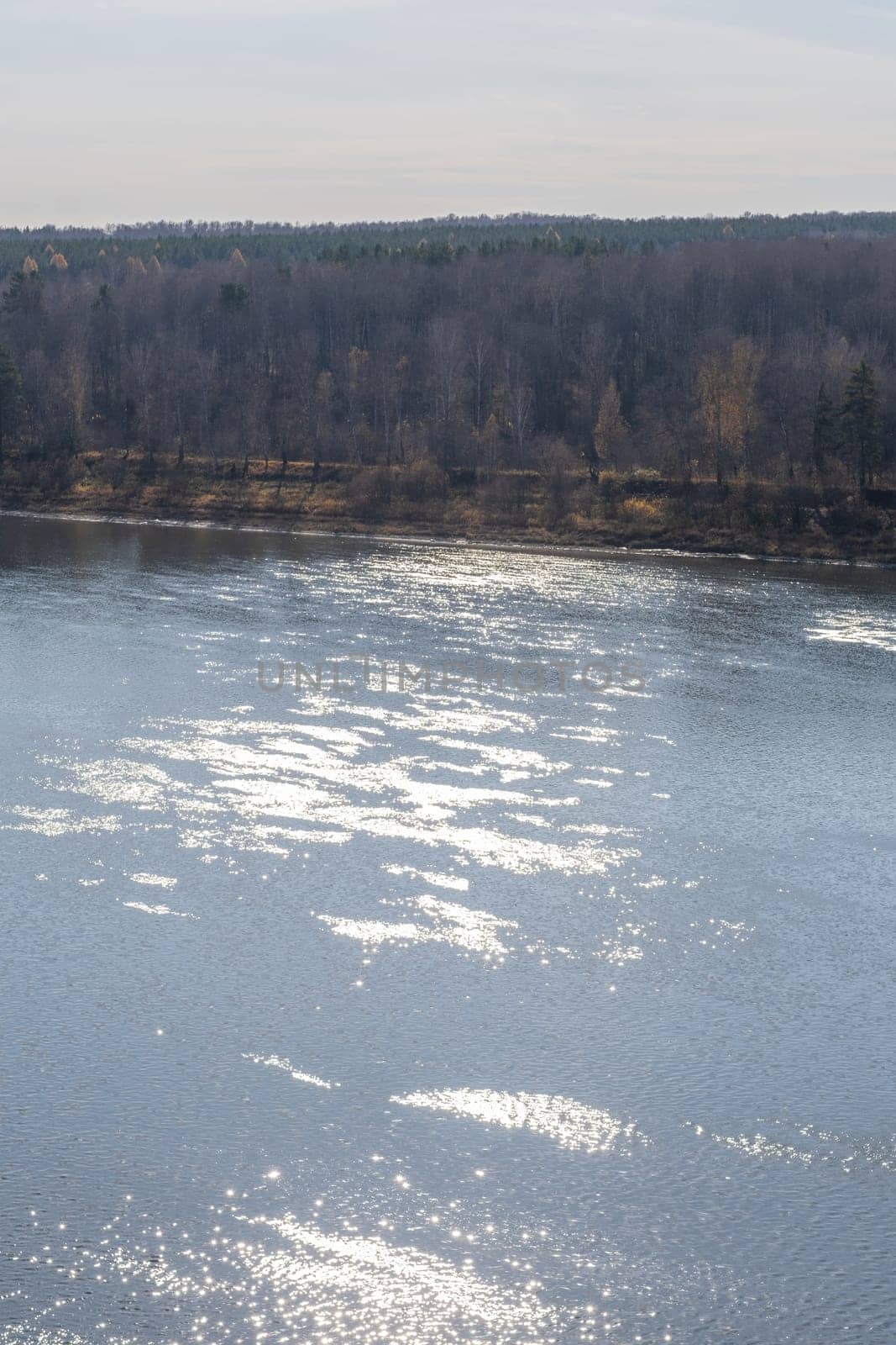 Beautiful, wide autumn river among forests and rocky shore. A calm and quiet place with autumn colors. Reflection of clouds in the water in good weather