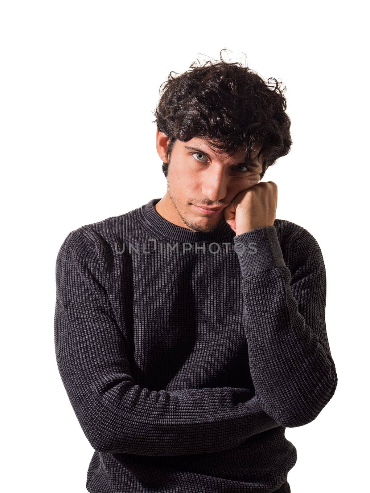 A man with curly hair wearing a black sweater, thinking, or disappointed or sad, in studio shot, looking at camera