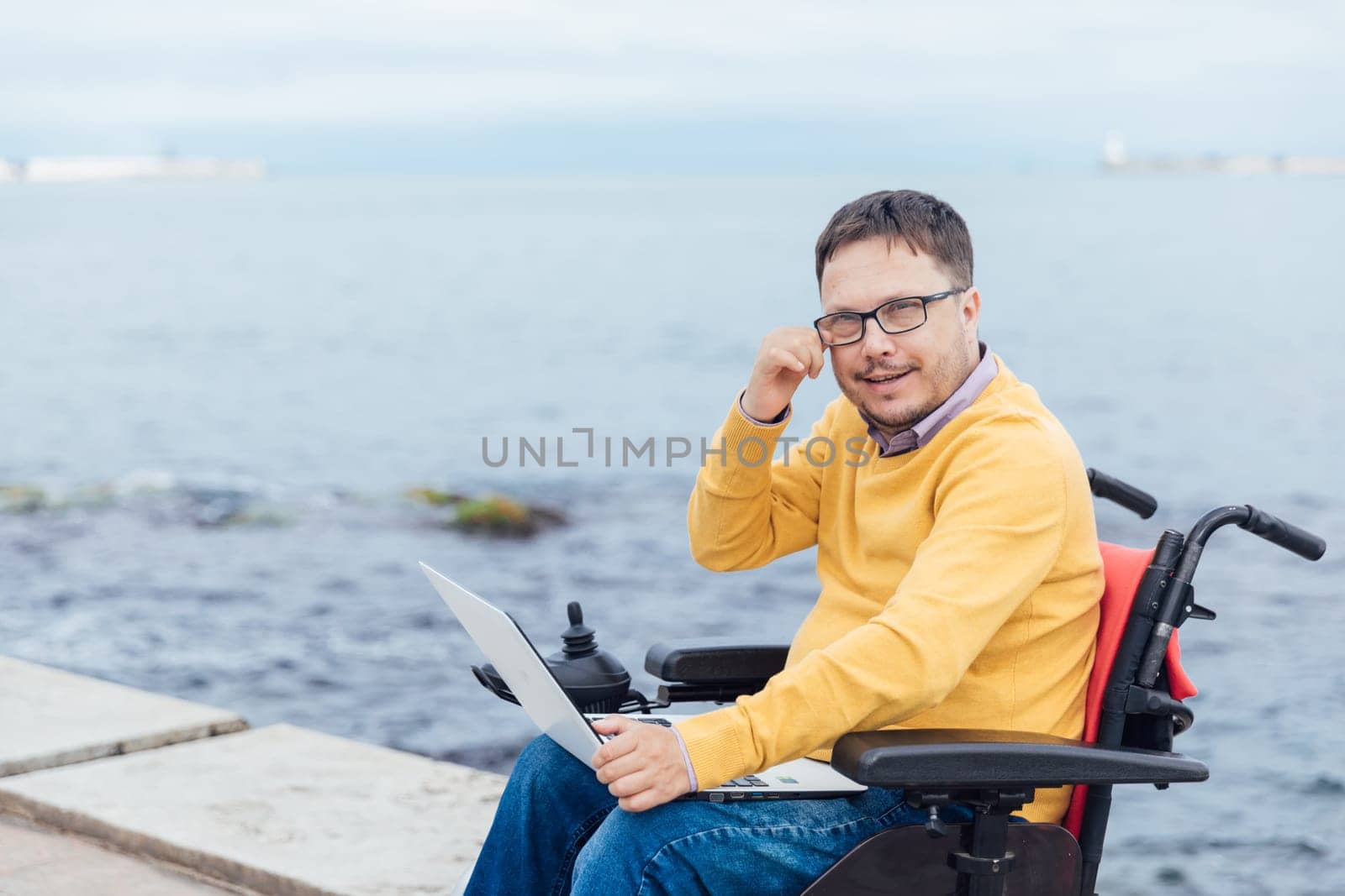 A person with disabilities with a laptop by the sea